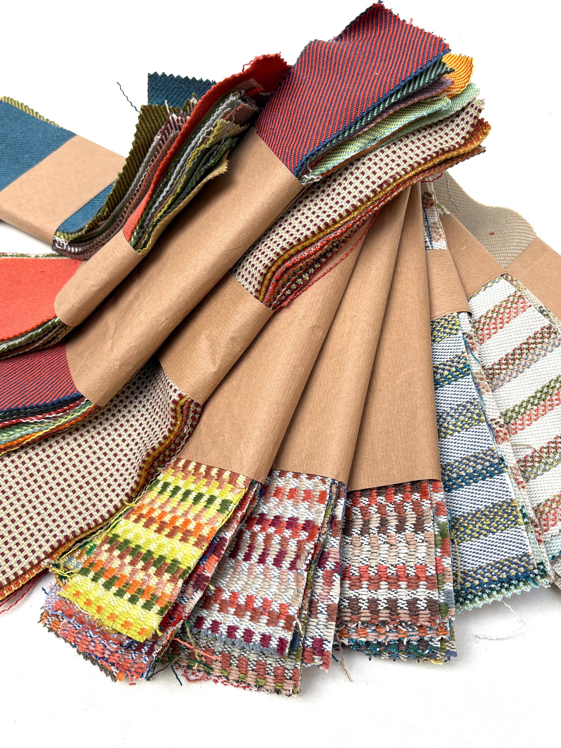 Various fabric samples are arranged in layers on a white background
