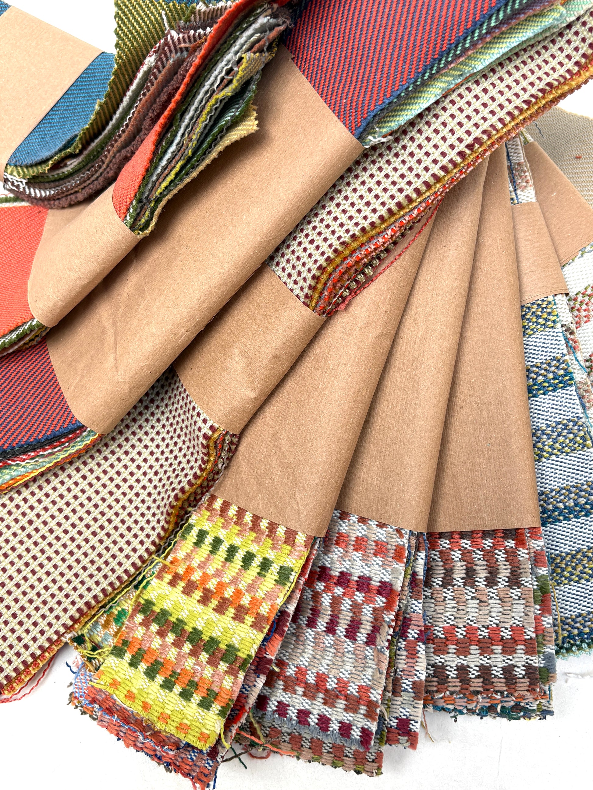 Colourful woven fabric samples are layered beside brown fabric pieces