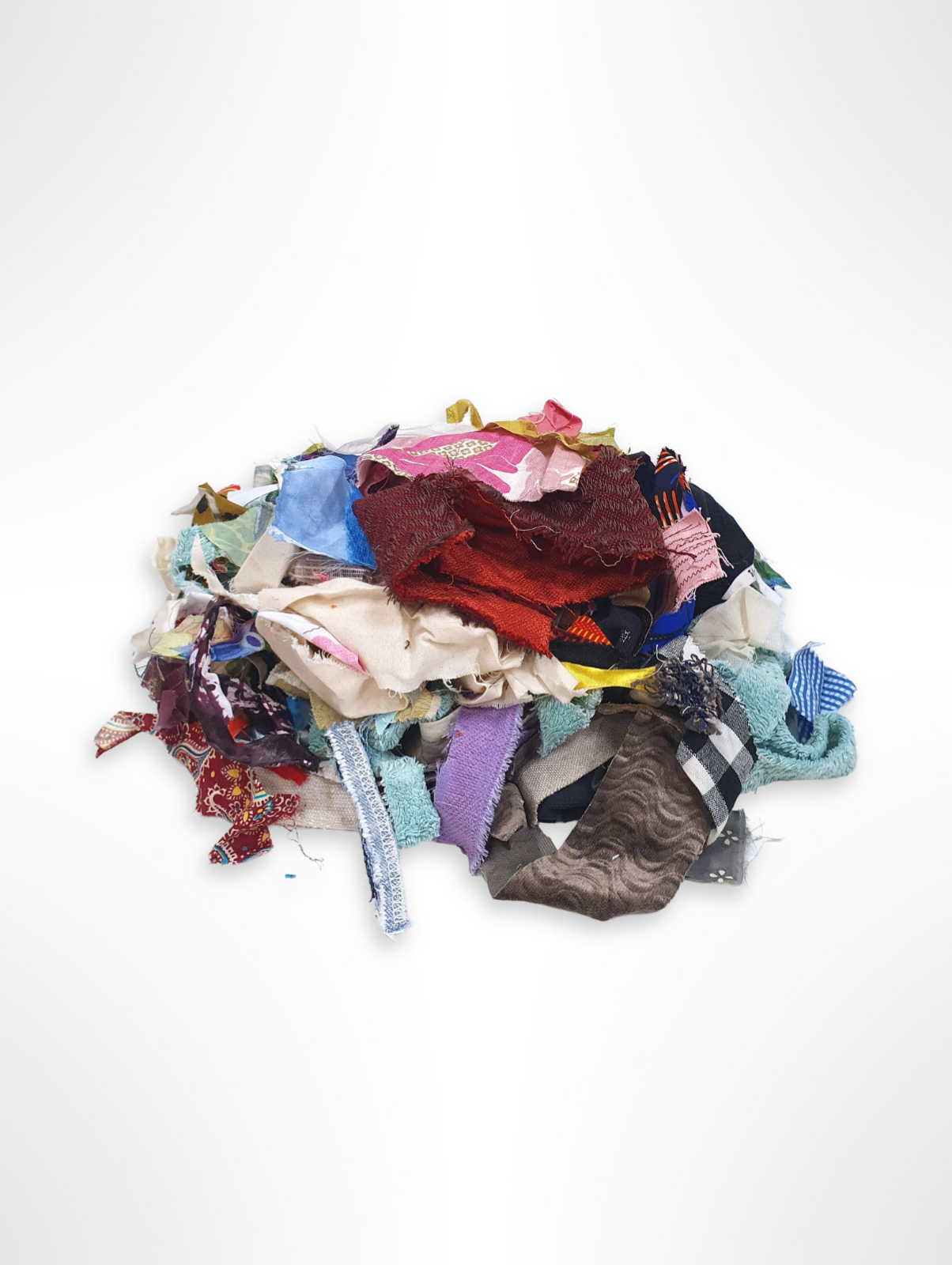 Pile of mixed fabric offcuts in assorted colours and patterns on white.