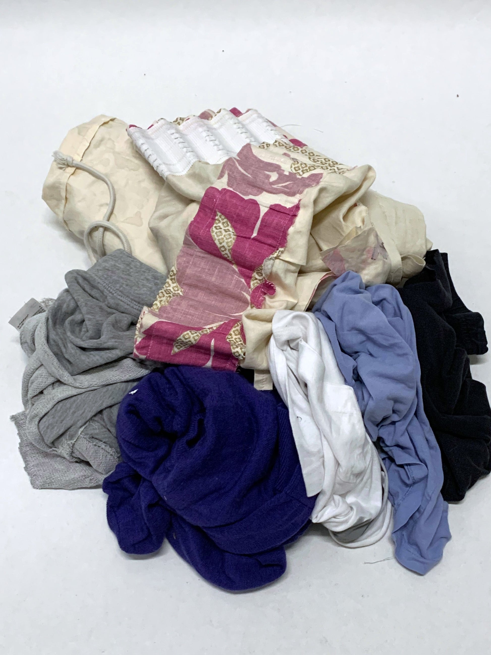 Pile of mixed fabric offcuts in assorted colours and soft textures on white.