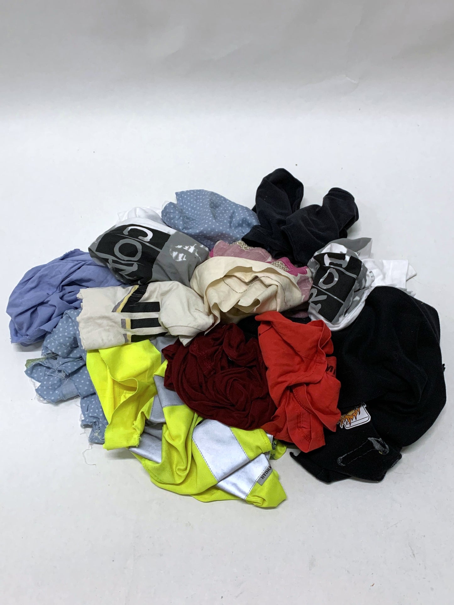 Pile of mixed fabric offcuts in assorted colours and printed fabrics on white.