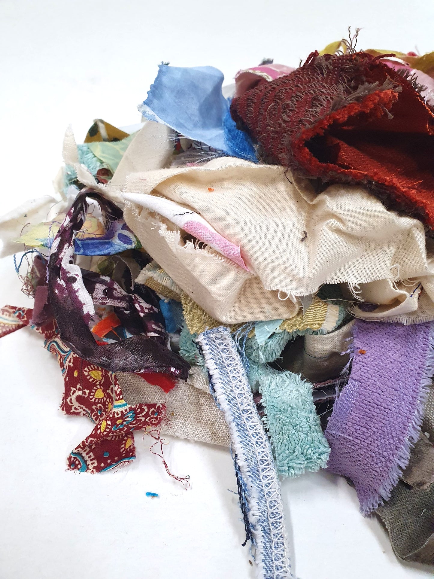 Close-up of a pile of mixed fabric offcuts in assorted colours and textures.