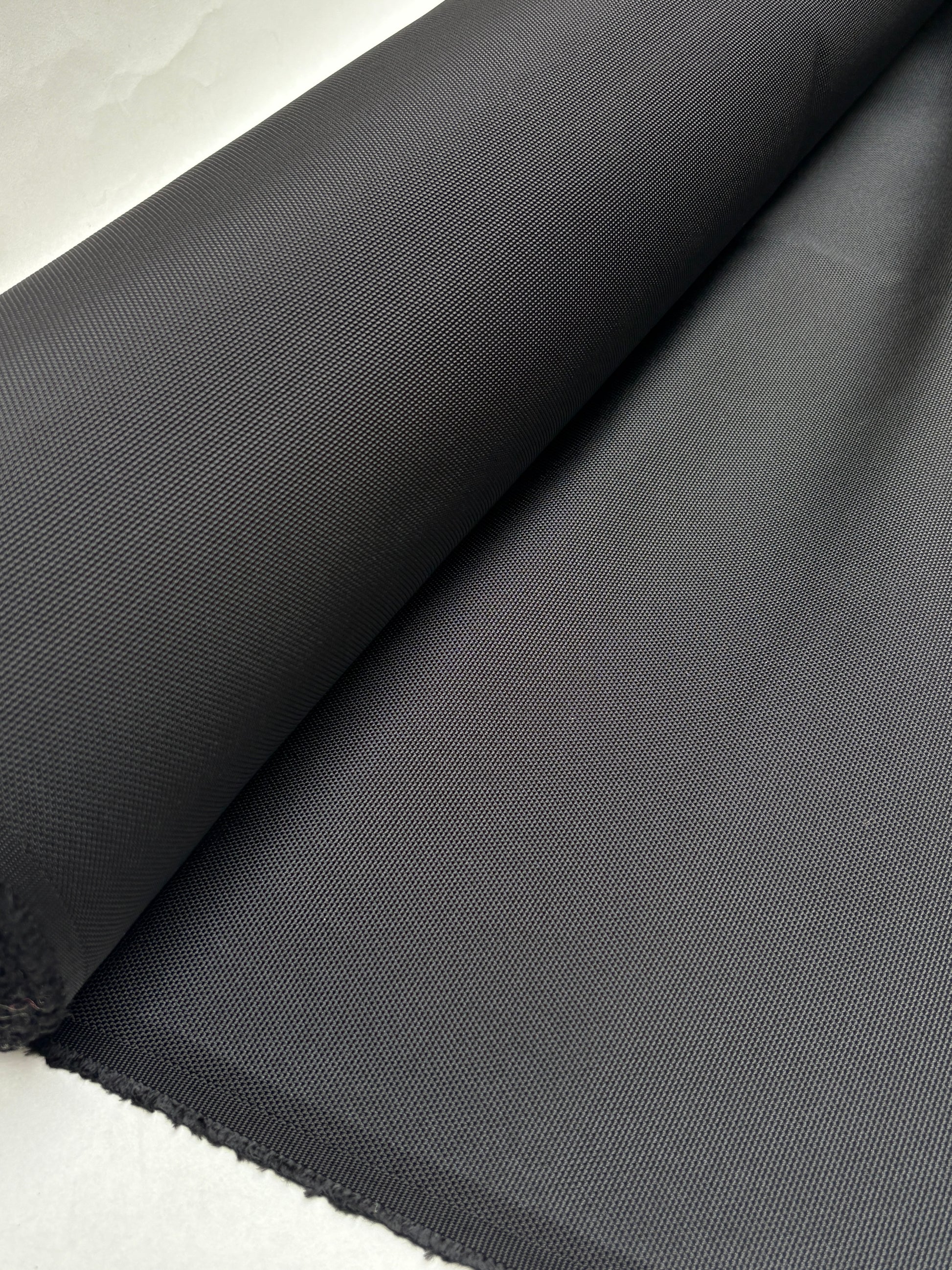 Black fabric is unrolled on a white surface