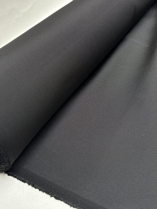 Black fabric is unrolled on a white surface