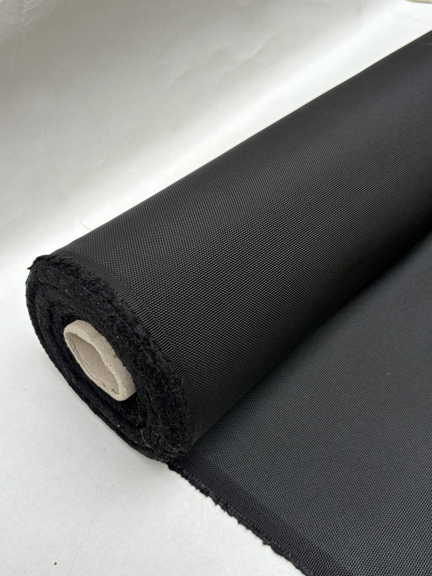 Dark textured fabric hangs from a rolled edge