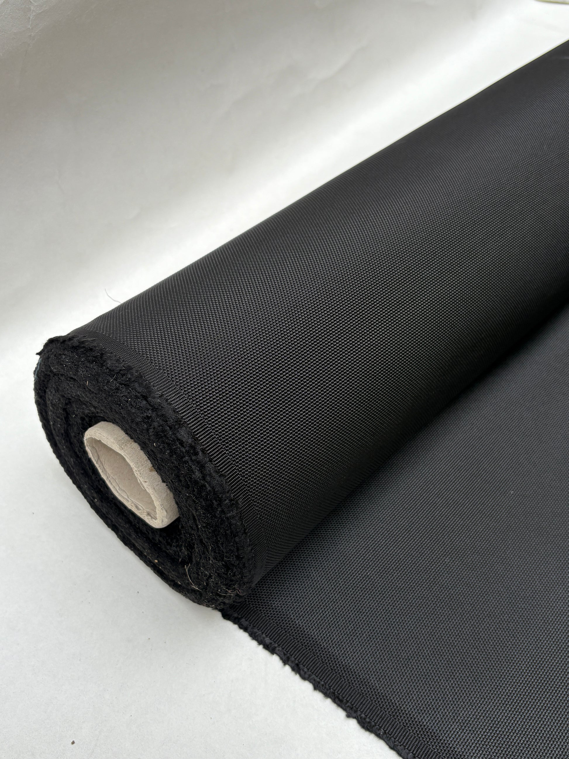 Dark textured fabric hangs from a rolled edge