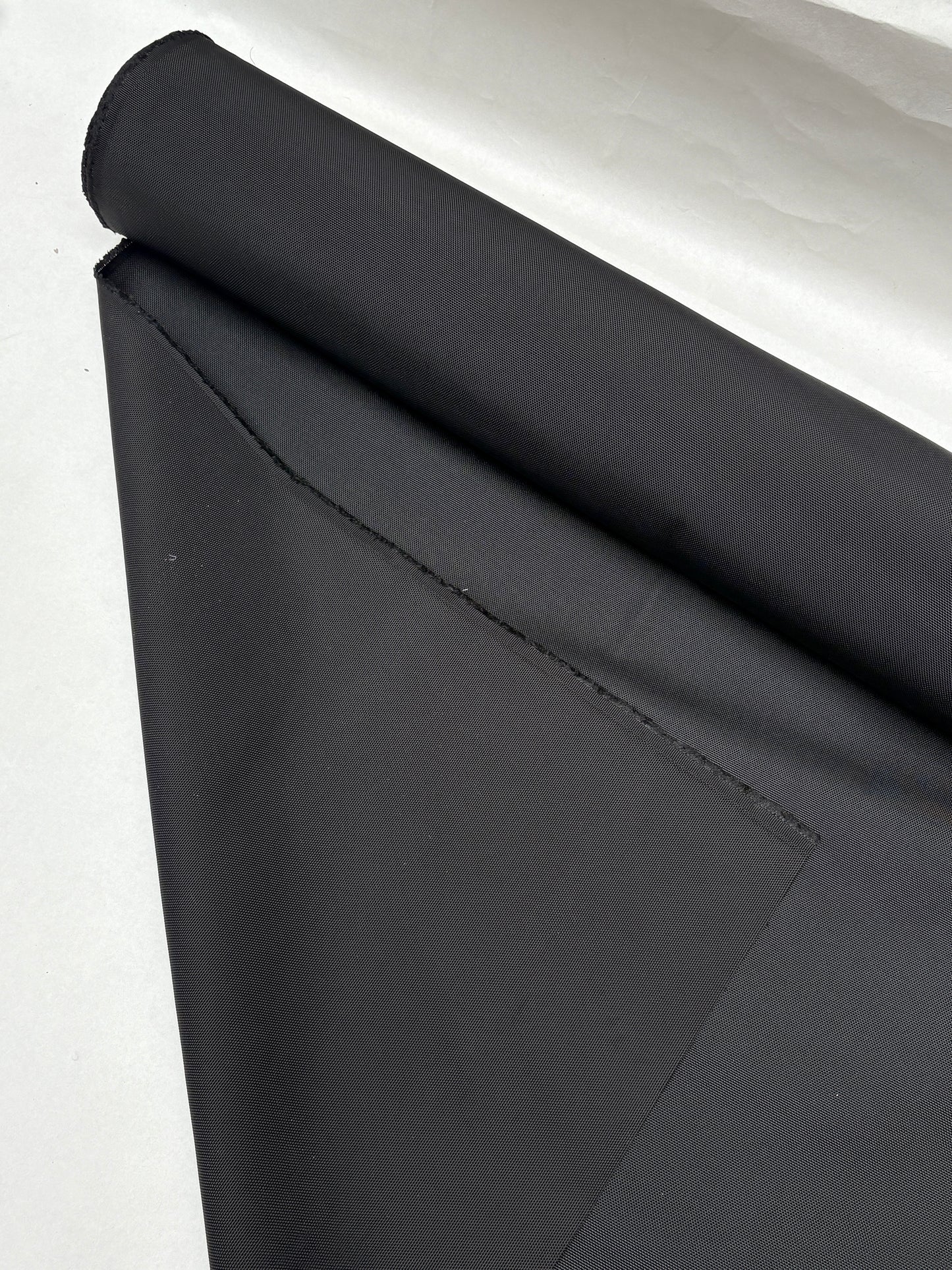 Black fabric is shown in folded and rolled views