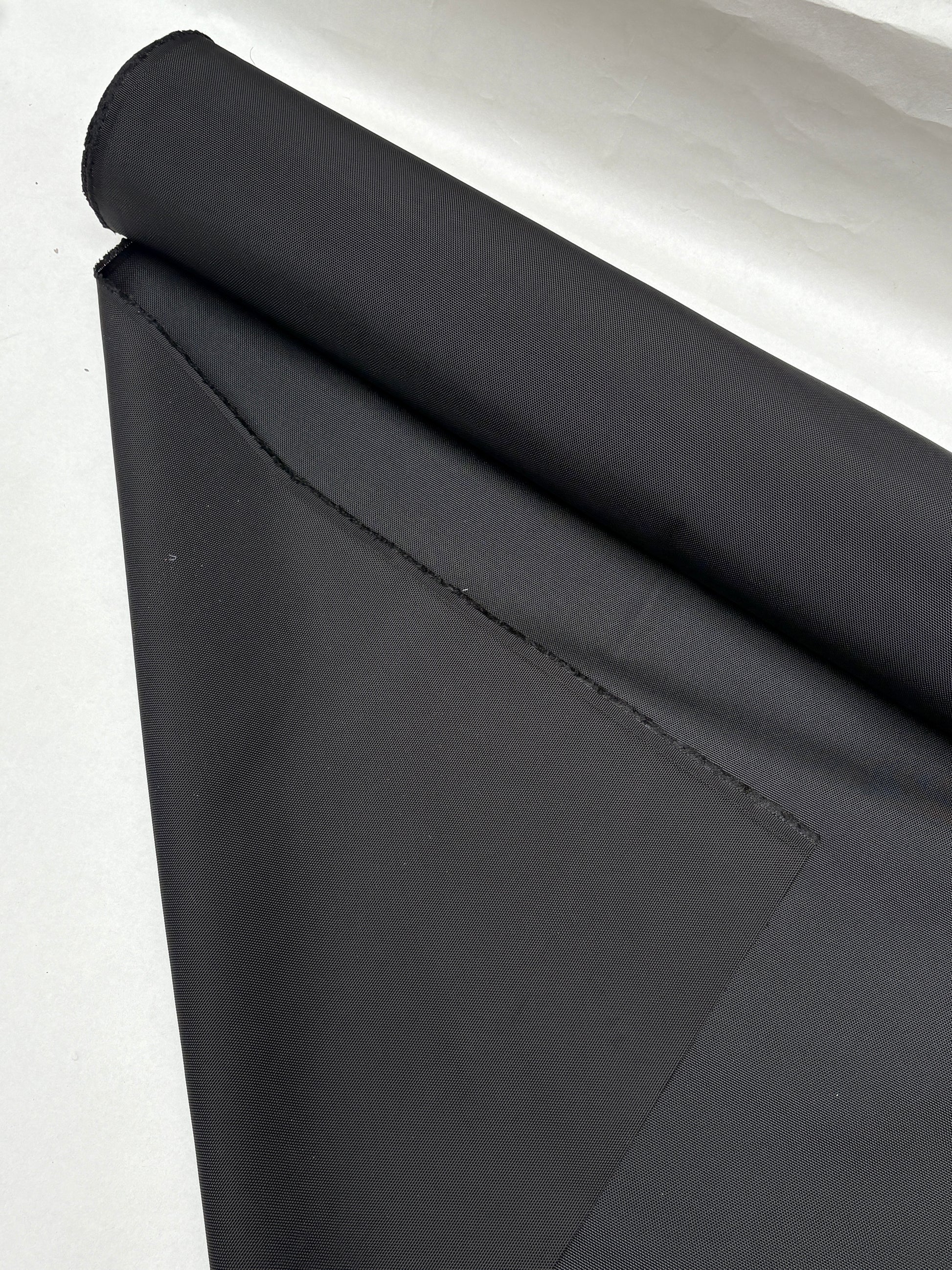 Black fabric is shown in folded and rolled views