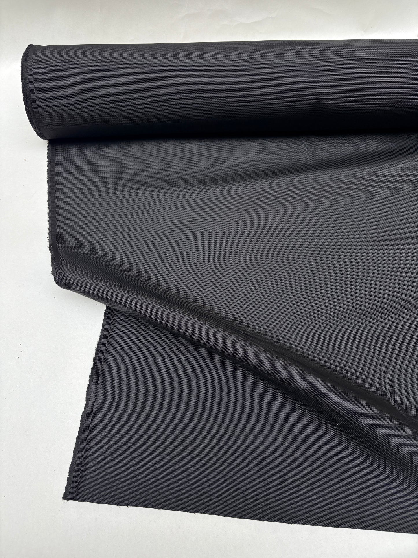 Black fabric is shown in folded and rolled views on white background