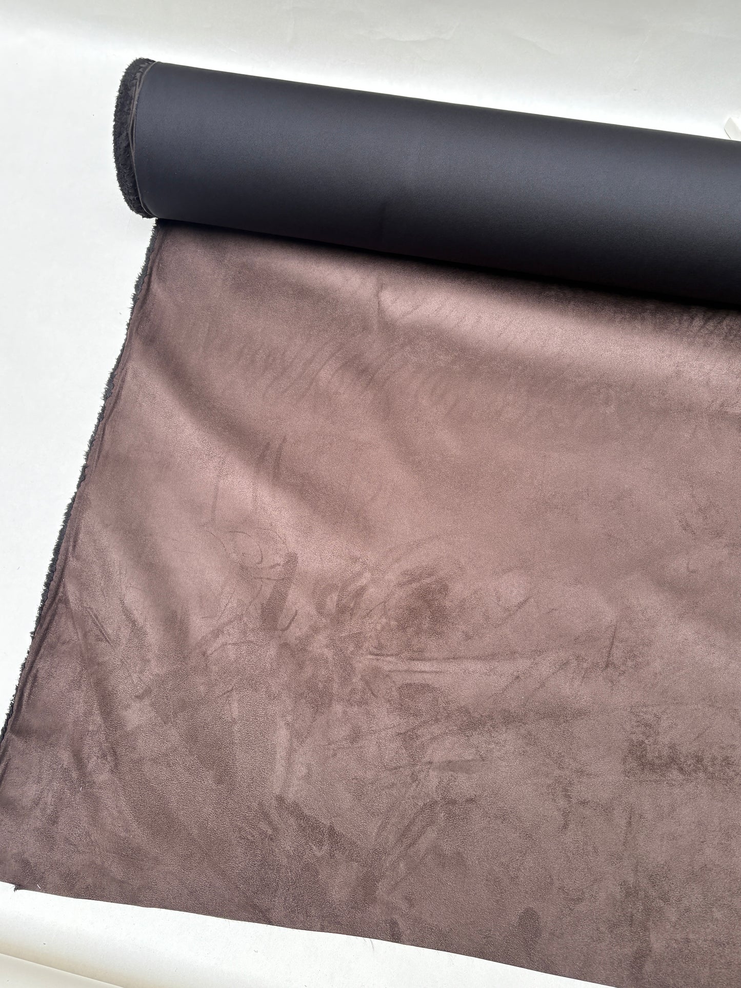 Brown suede-textured fabric hangs beneath a rolled fabric edge