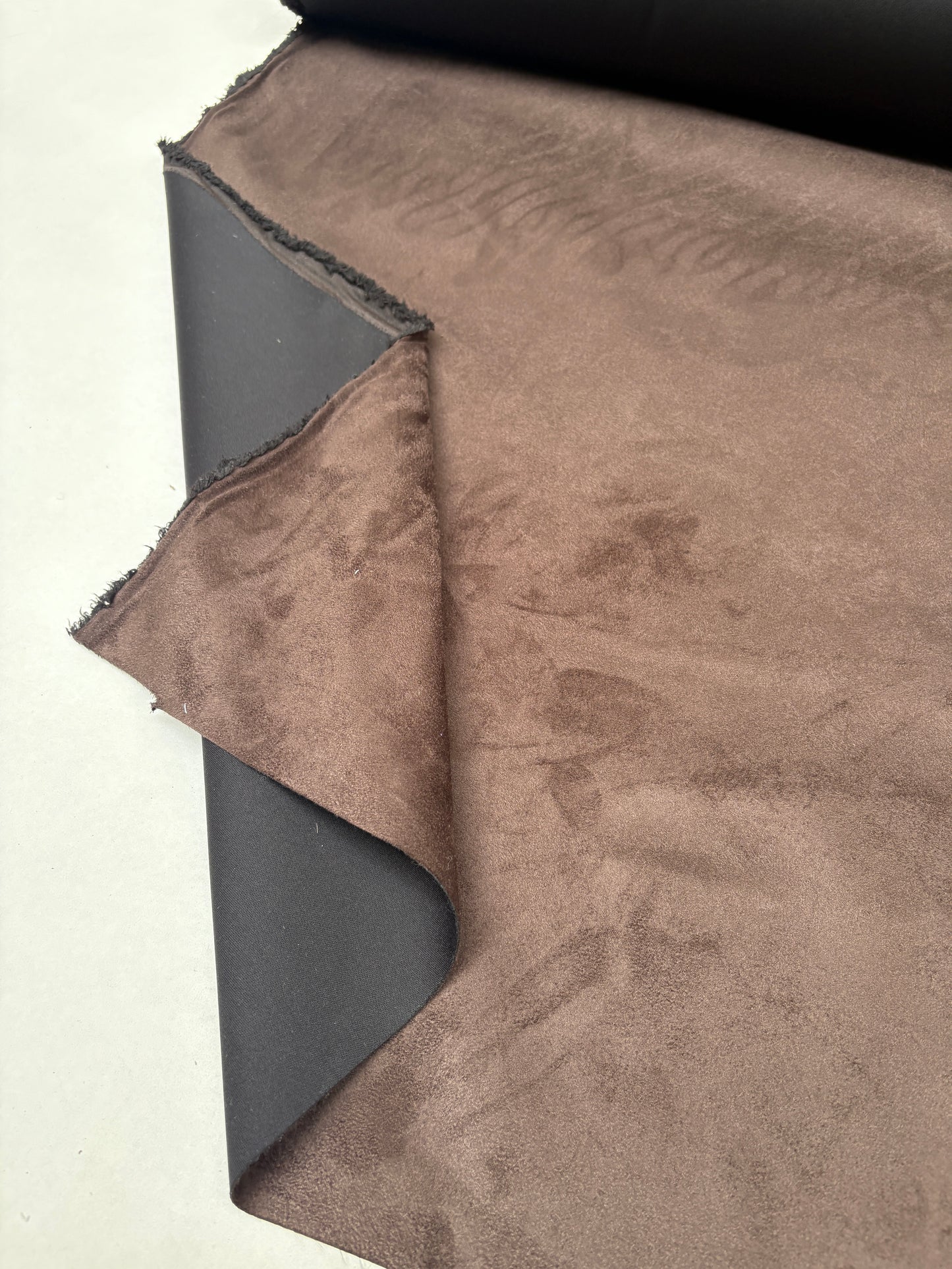 Suede-textured brown fabric is displayed with soft surface markings
