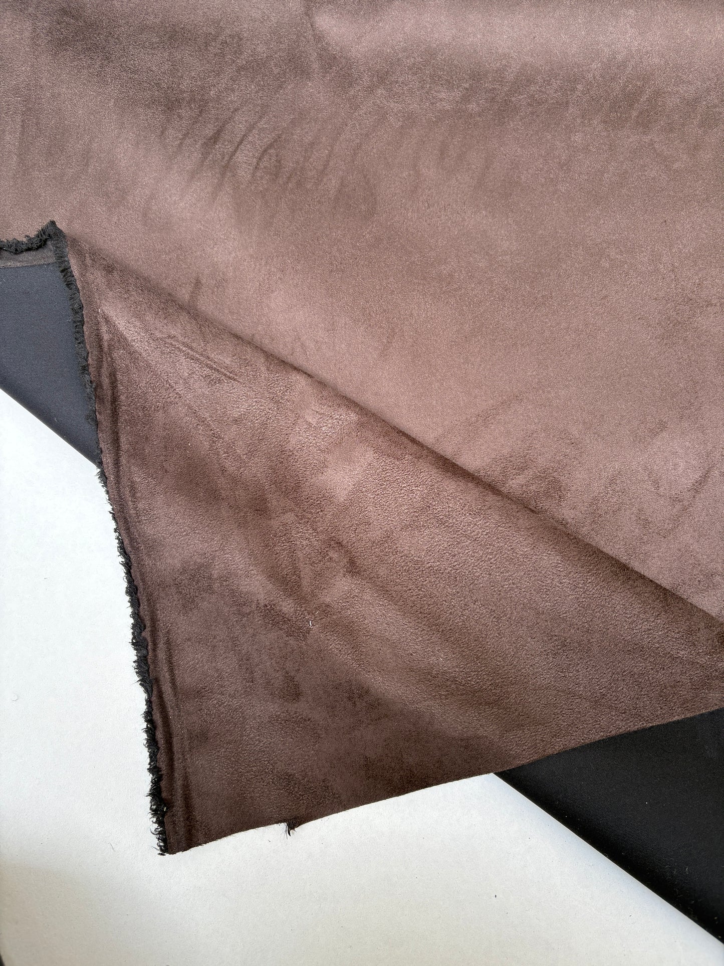 Brown fabric with a suede-like surface is shown hanging flat