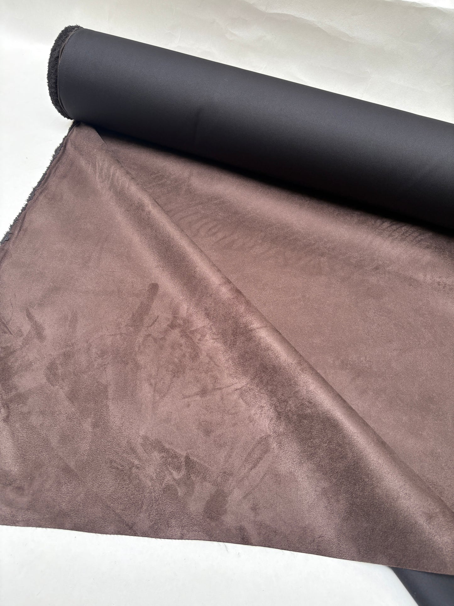 A brown fabric roll hangs open to show on a white background