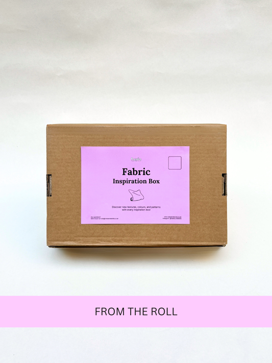 Brown paper box with pink label in front of white background with a pink banner on below the box