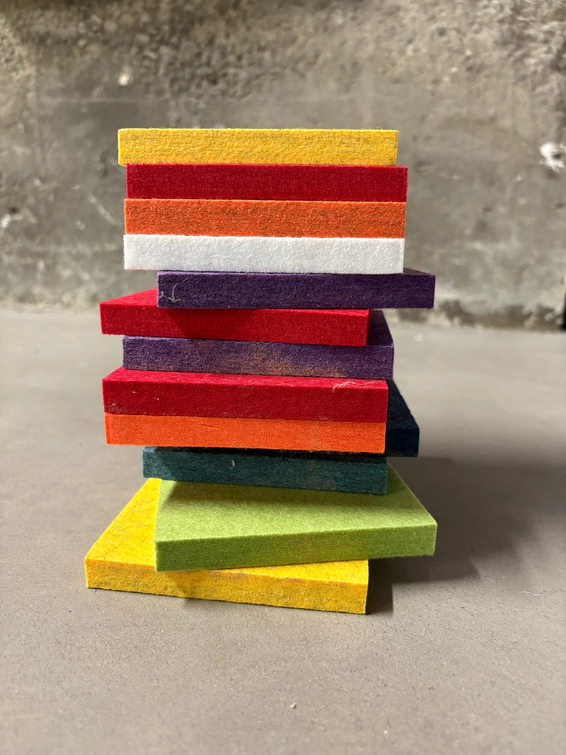 Coloured felt squares are stacked in detail on a white surface