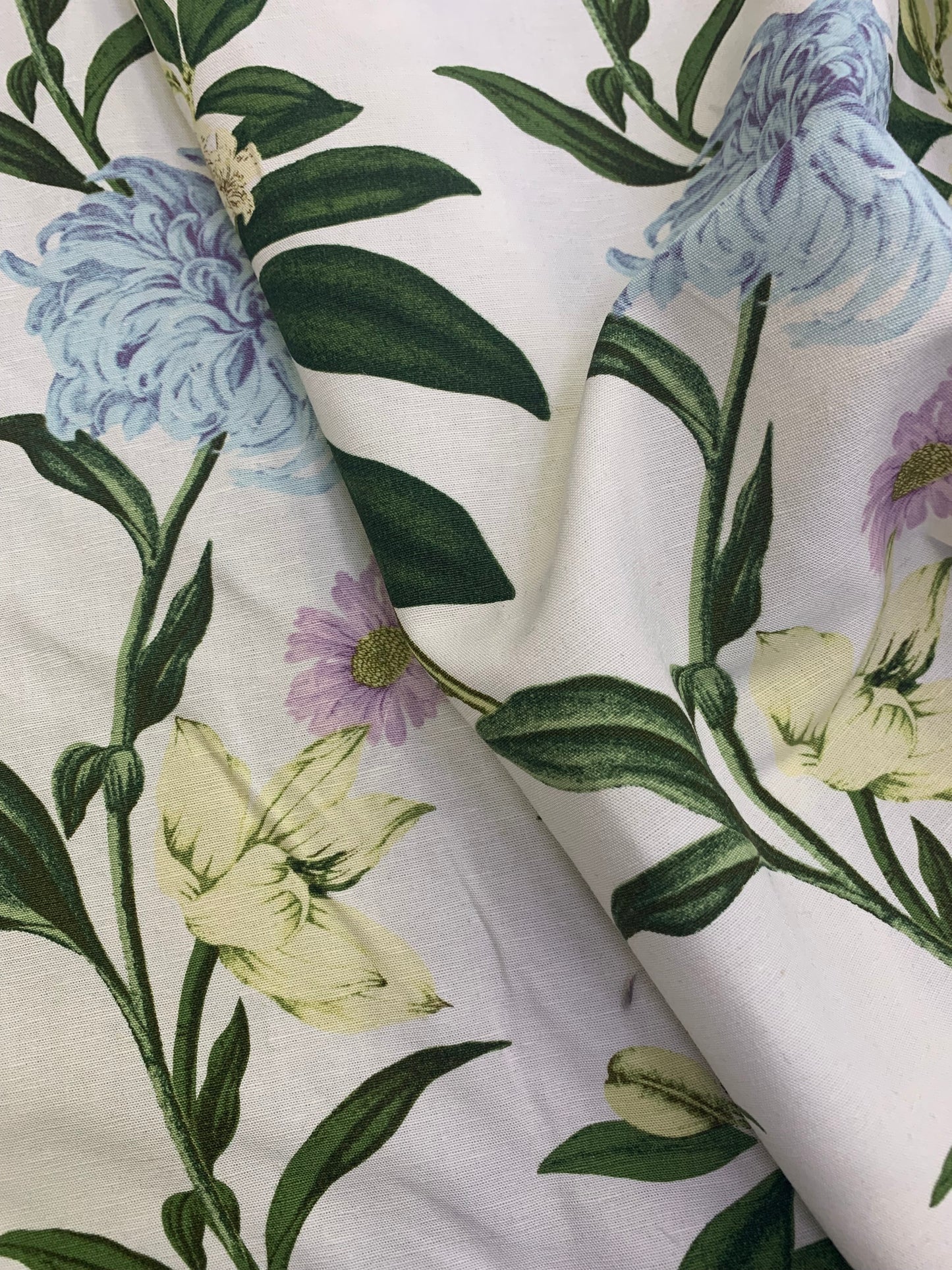 Printed fabric shows blue flowers and green leaves in close-up