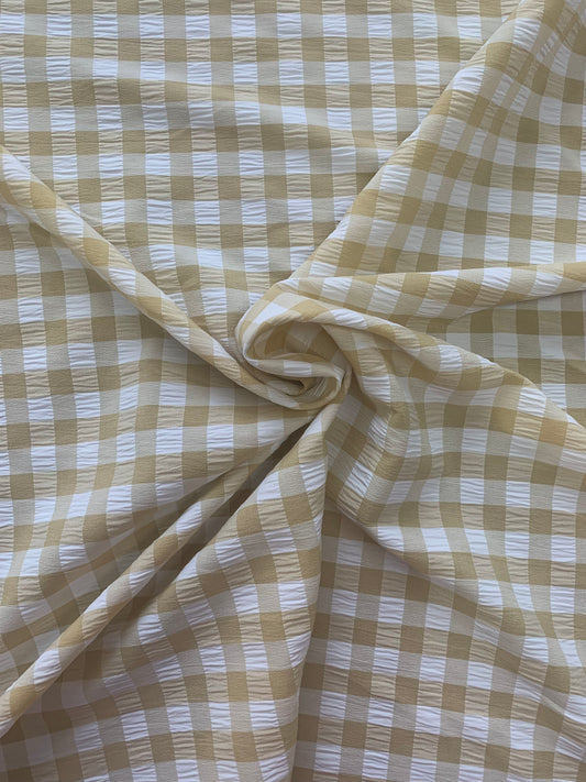 Beige and white gingham fabric is gathered into soft folds