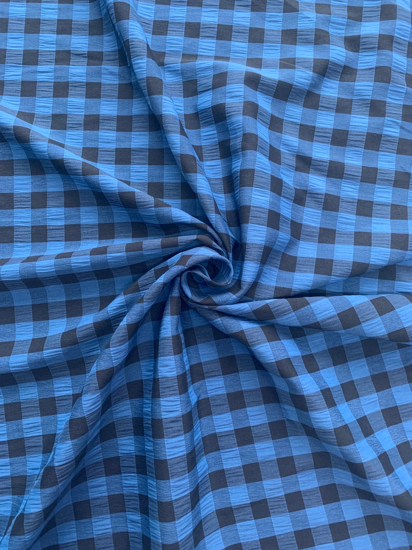 Blue and black checked fabric is gathered into soft folds