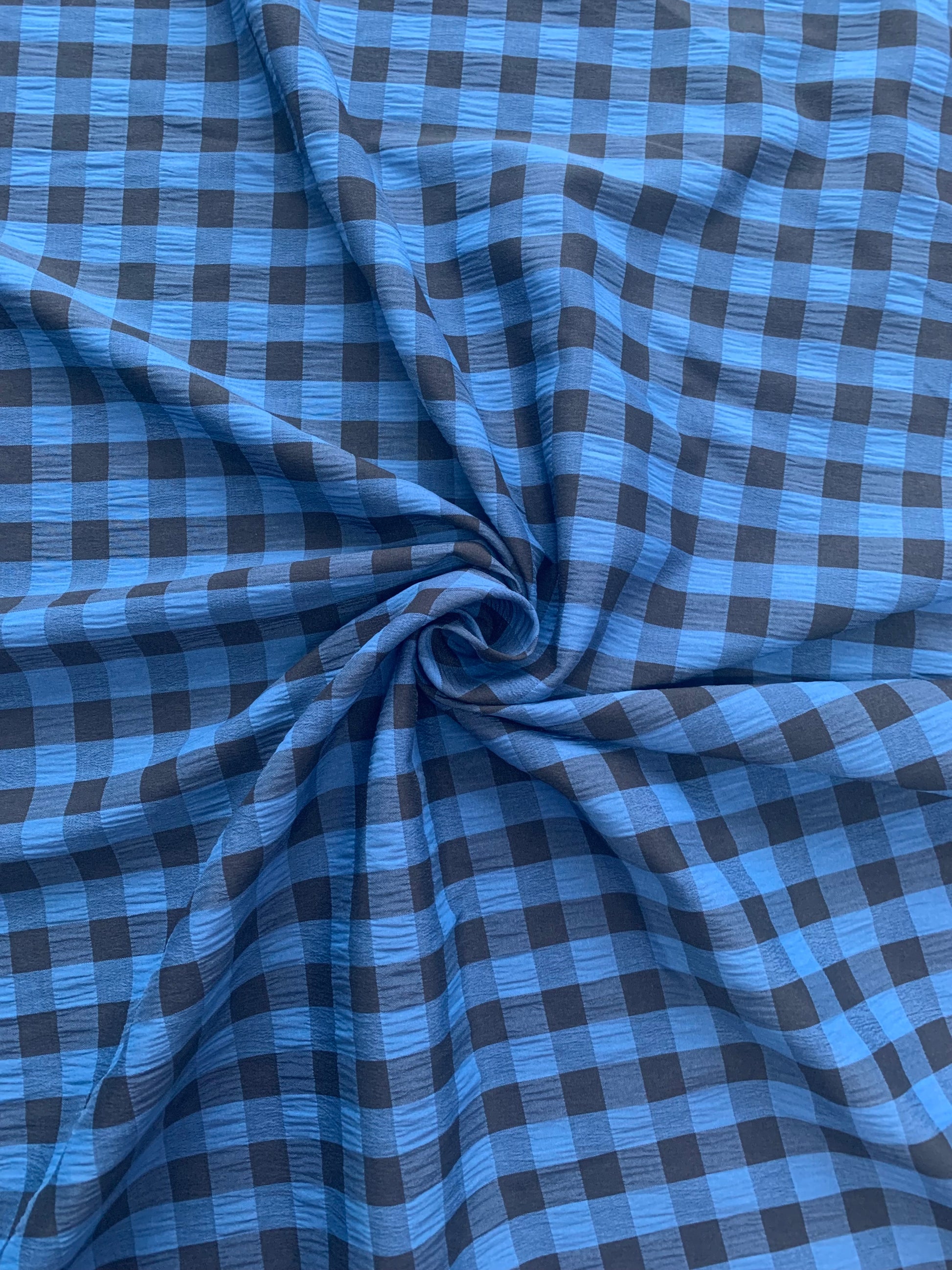 Blue and black checked fabric is gathered into soft folds