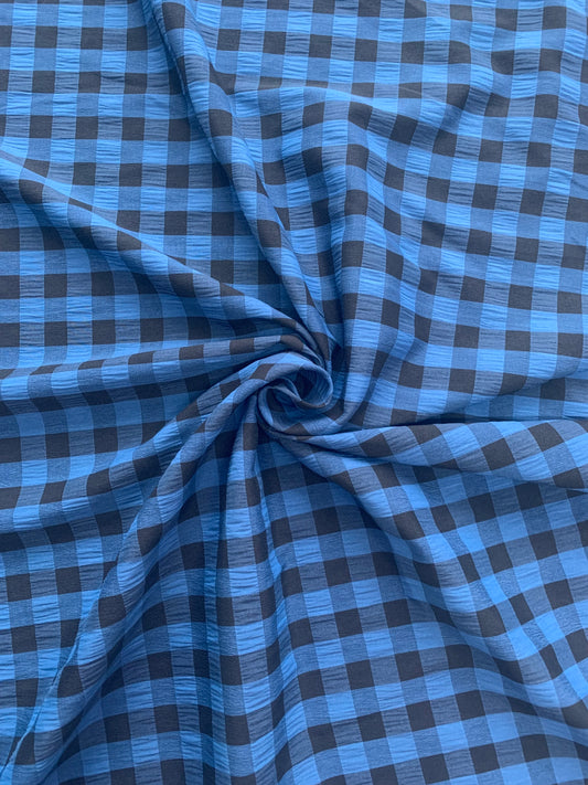 Blue and black checked fabric is gathered into soft folds