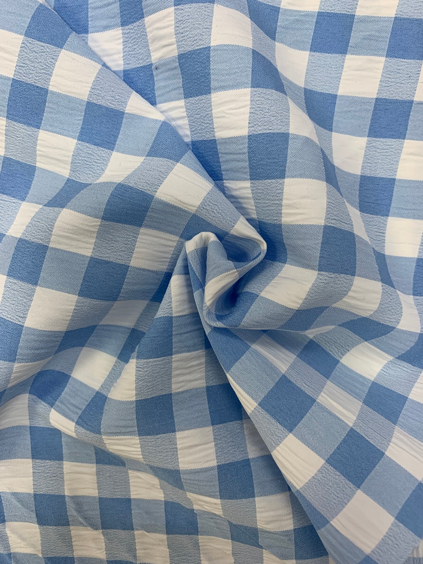 Light blue and white gingham fabric is folded in soft layers