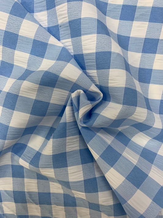 Light blue and white gingham fabric is folded in soft layers