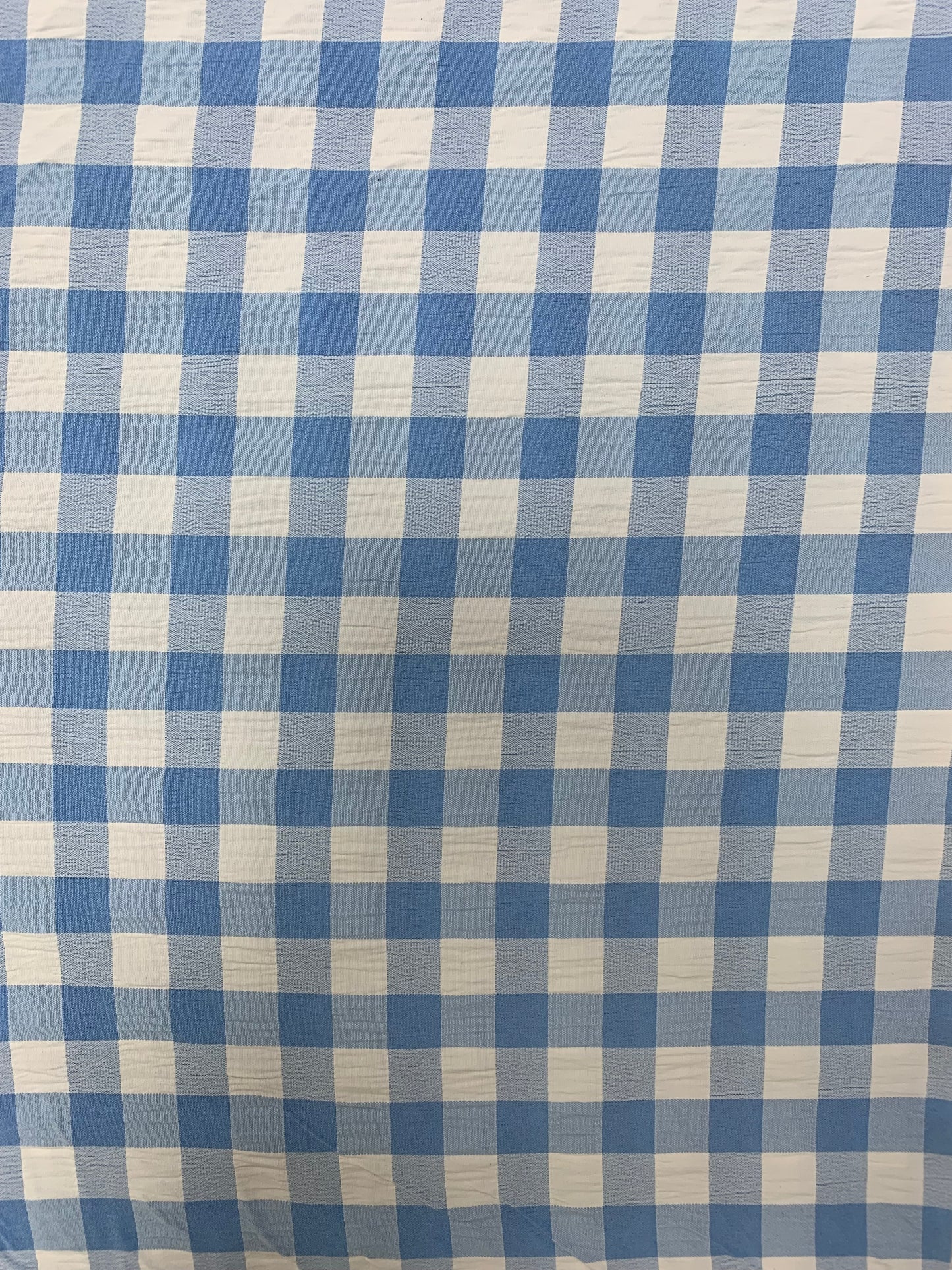 Light blue and white gingham fabric is folded in soft layers