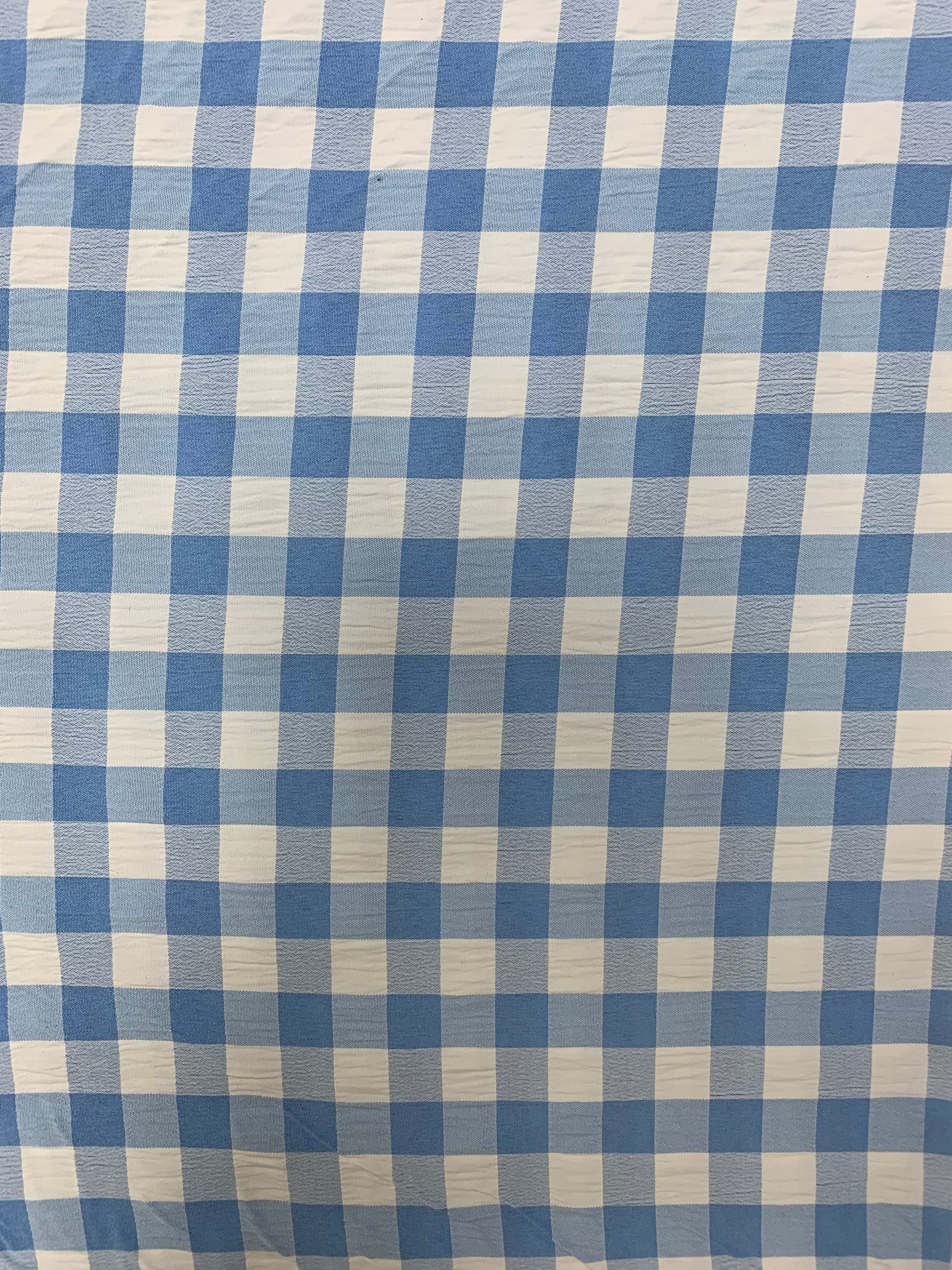 Light blue and white gingham fabric is folded in soft layers