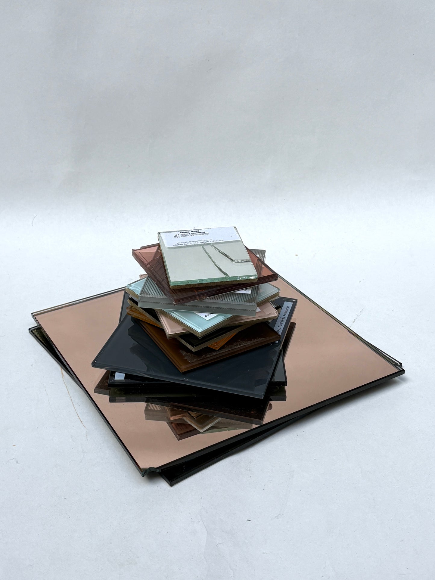 Mixed glass and mirror samples displayed on a white surface
