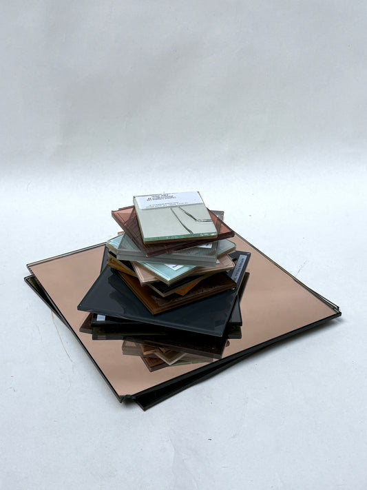 Mixed glass and mirror samples displayed on a white surface