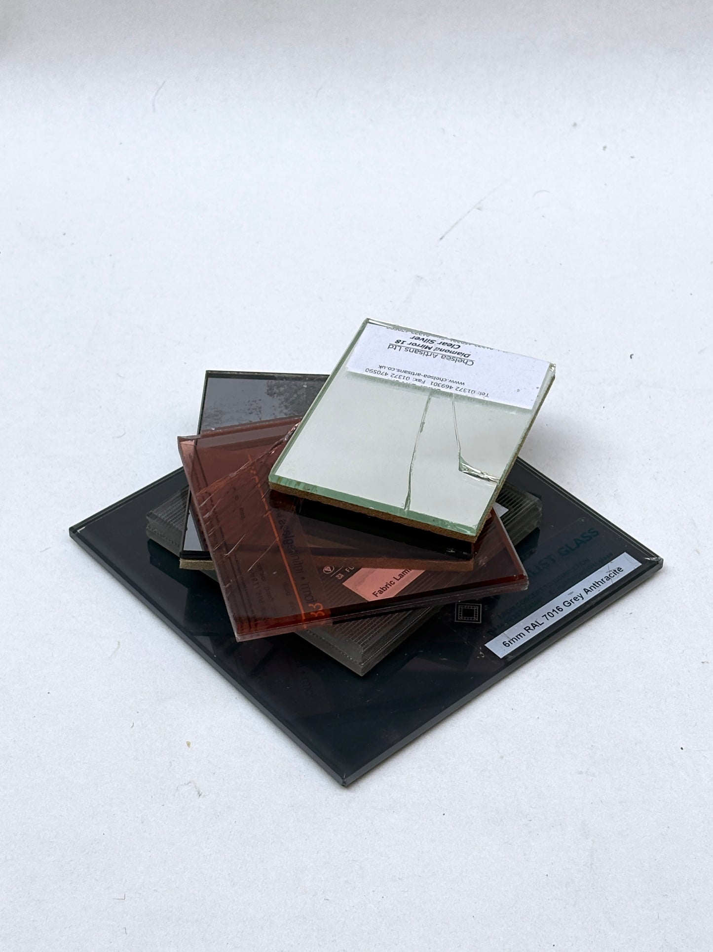 Assorted tinted glass and mirror pieces sit on a white background