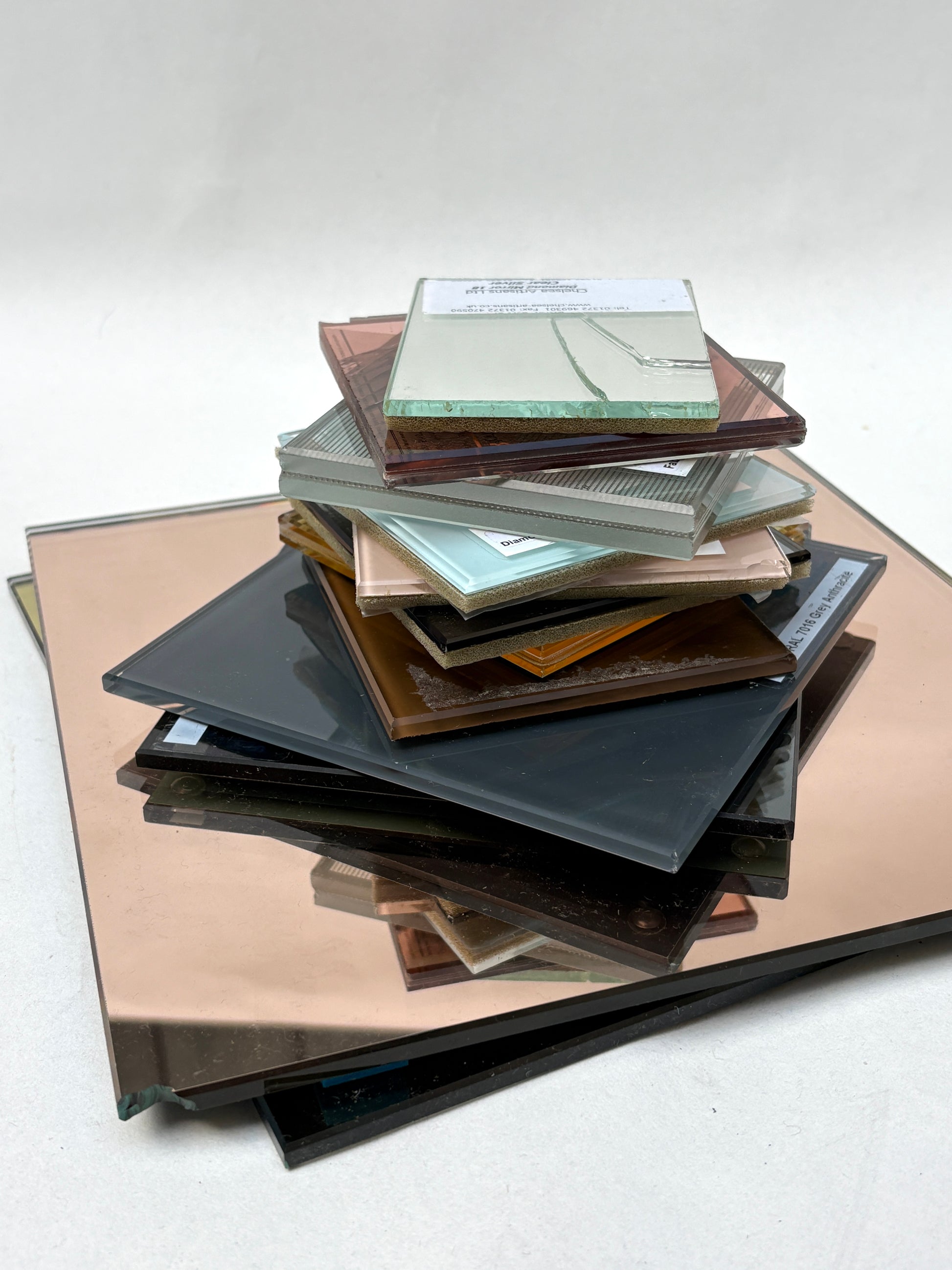 Glass and mirror samples stacked on a white background