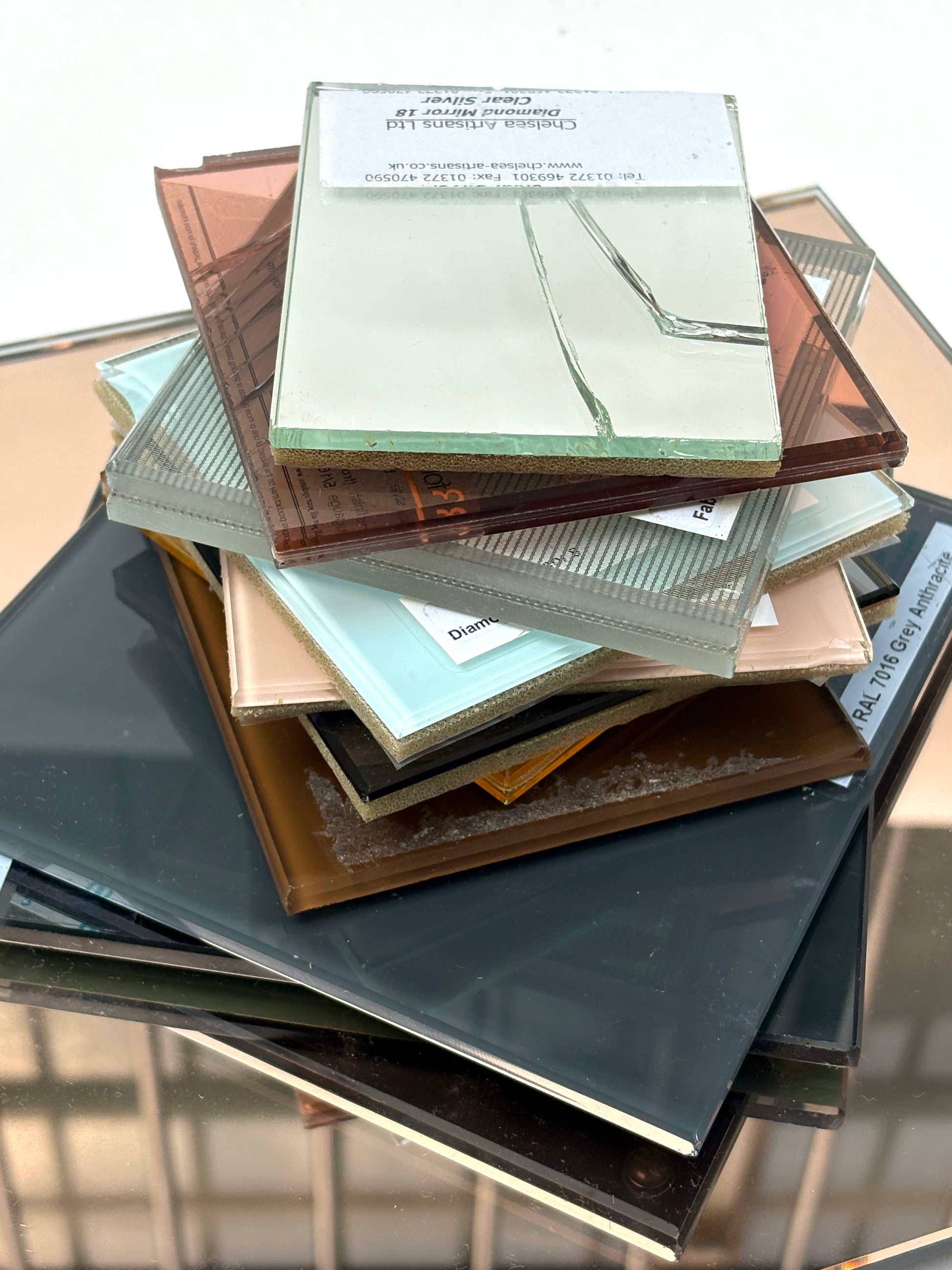Close-up of an assorted tinted glass and mirror pieces on a white surface