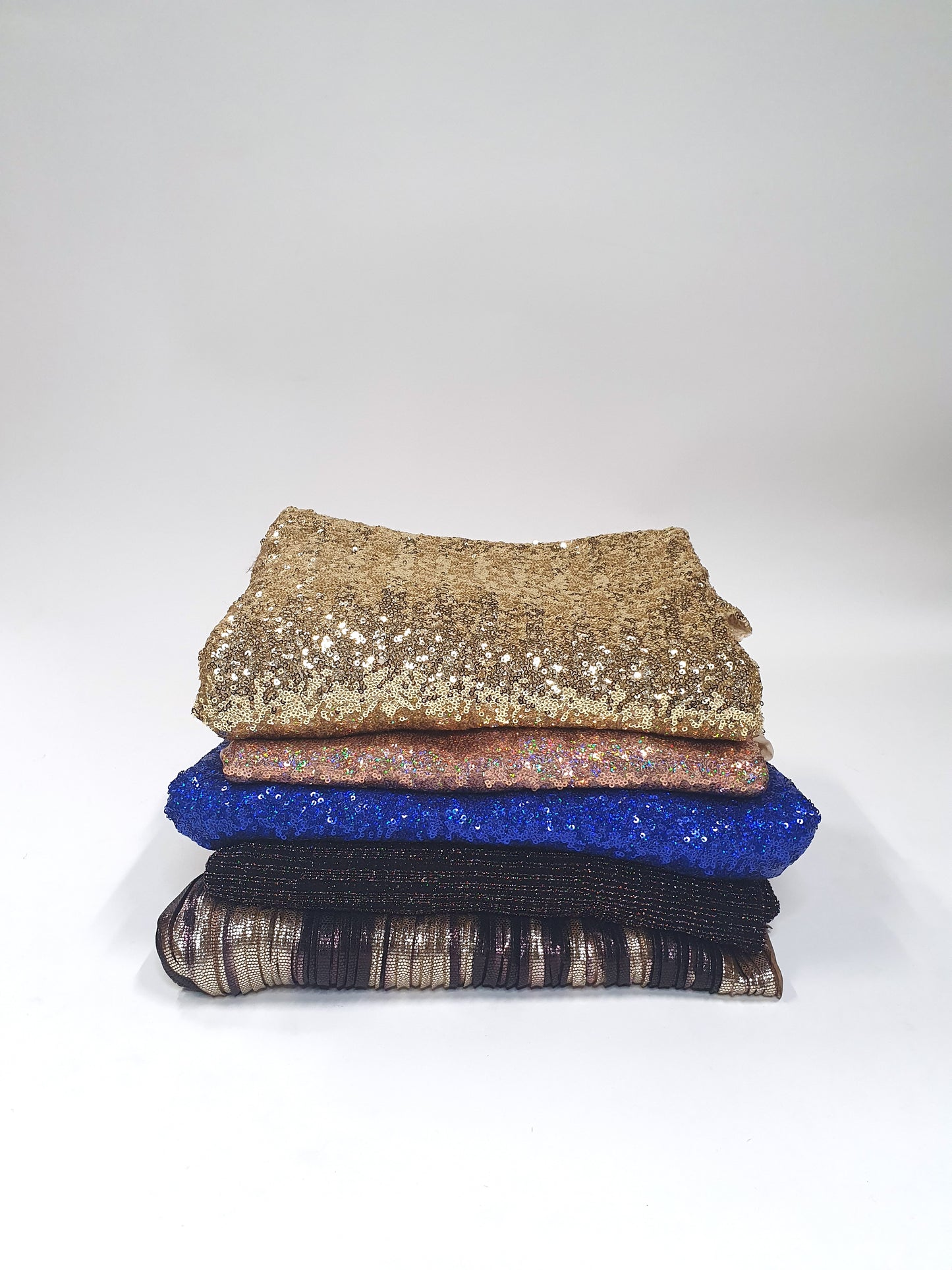 Pile of folded glitter fabric with gold, pink, blue, and black