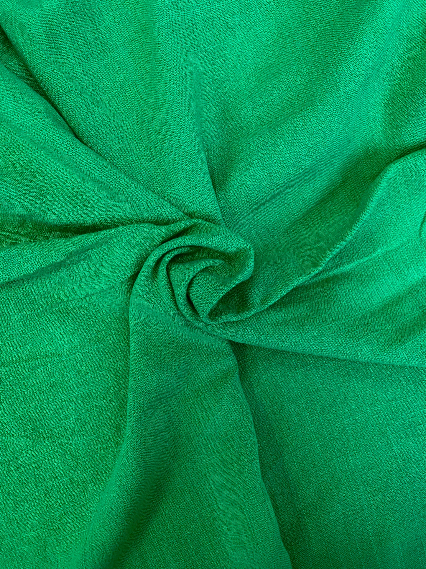 A close fabric study of green cloth shaped in loose folds.