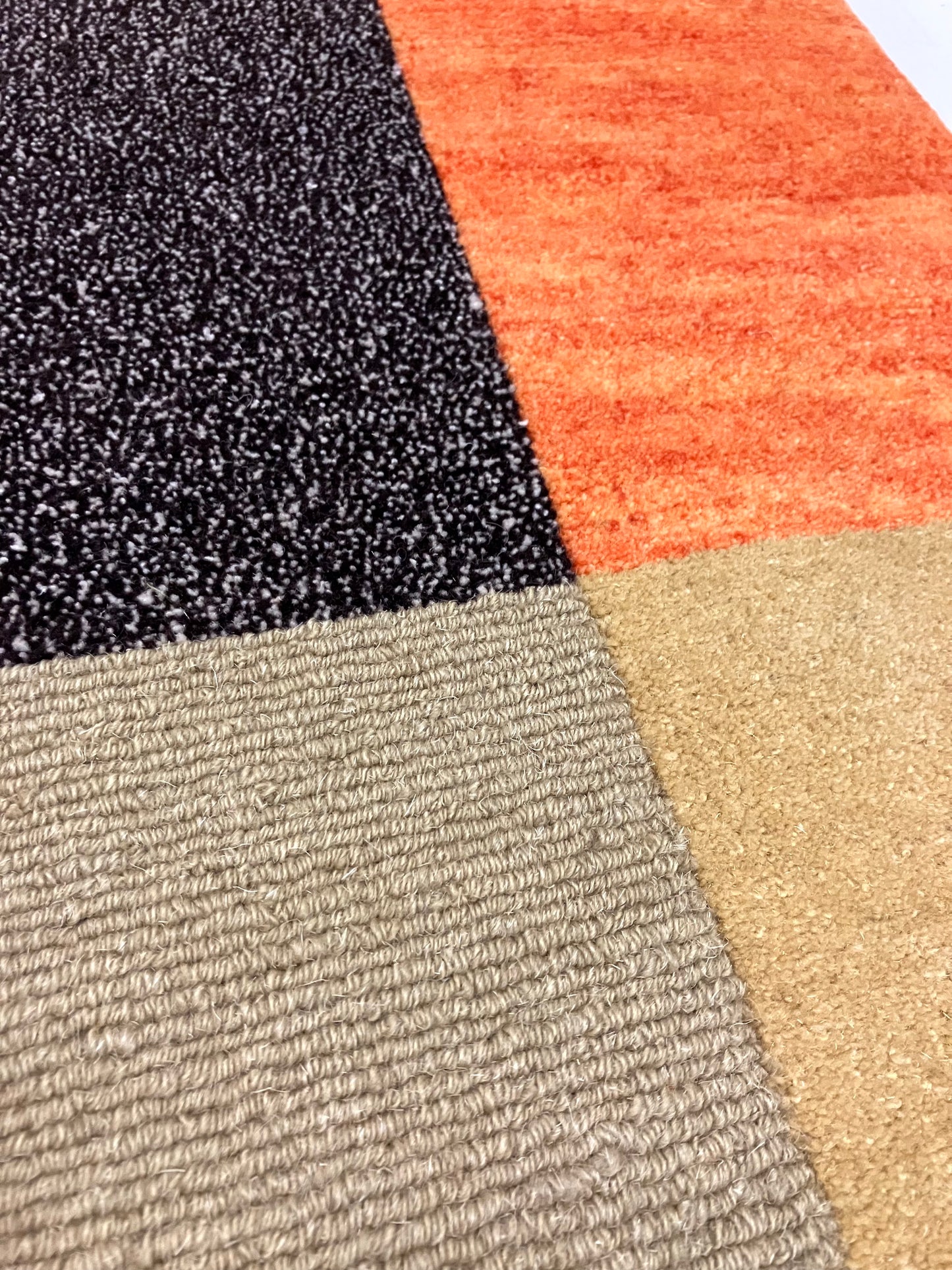 	Close-up view shows carpet sample sections in orange, black, beige, and brown