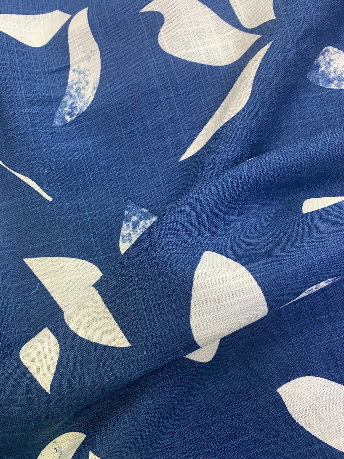 Blue fabric with an abstract cream print shown in soft folds.