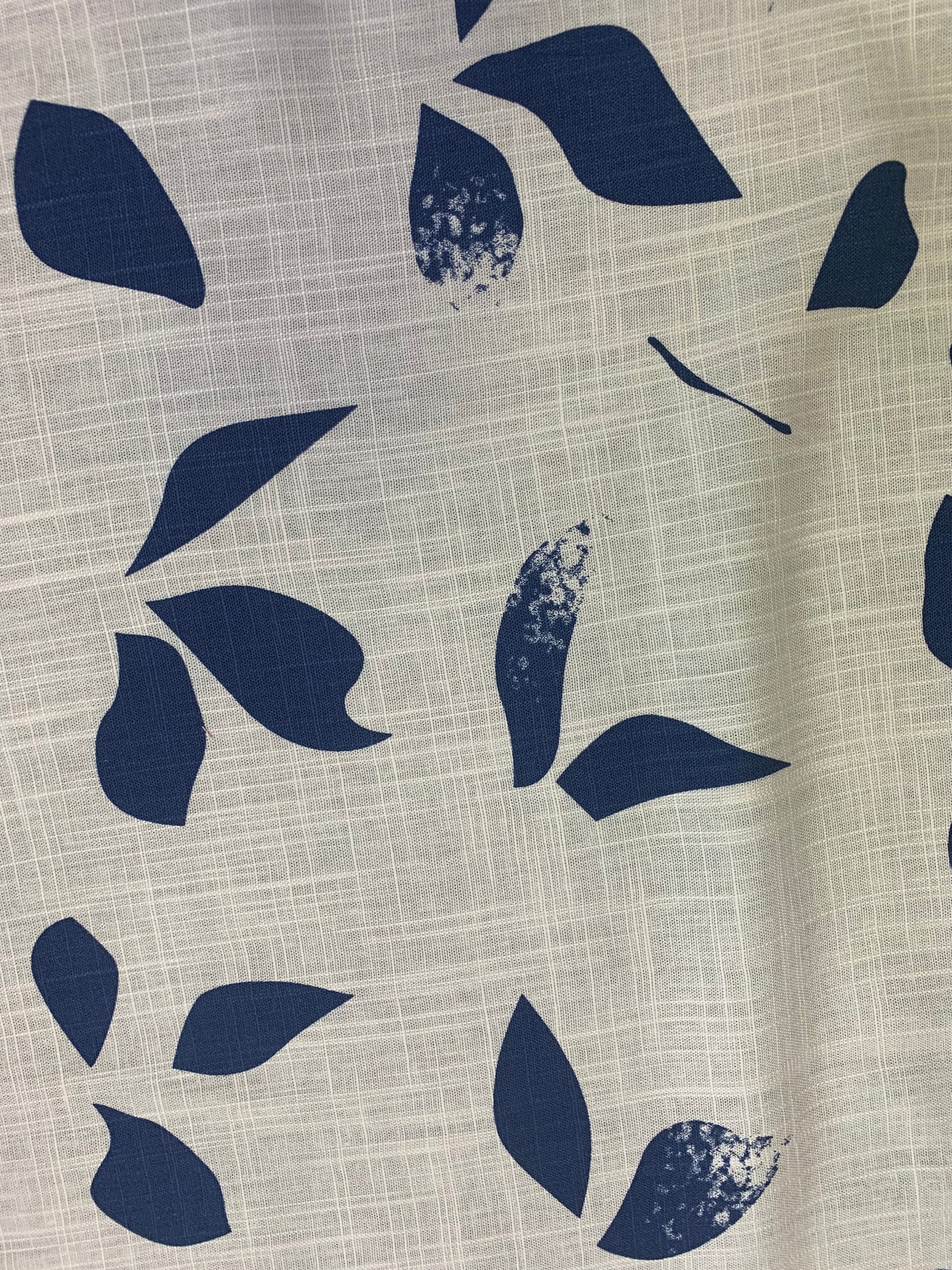 Ivory fabric with dark leaf shapes is folded in close-up