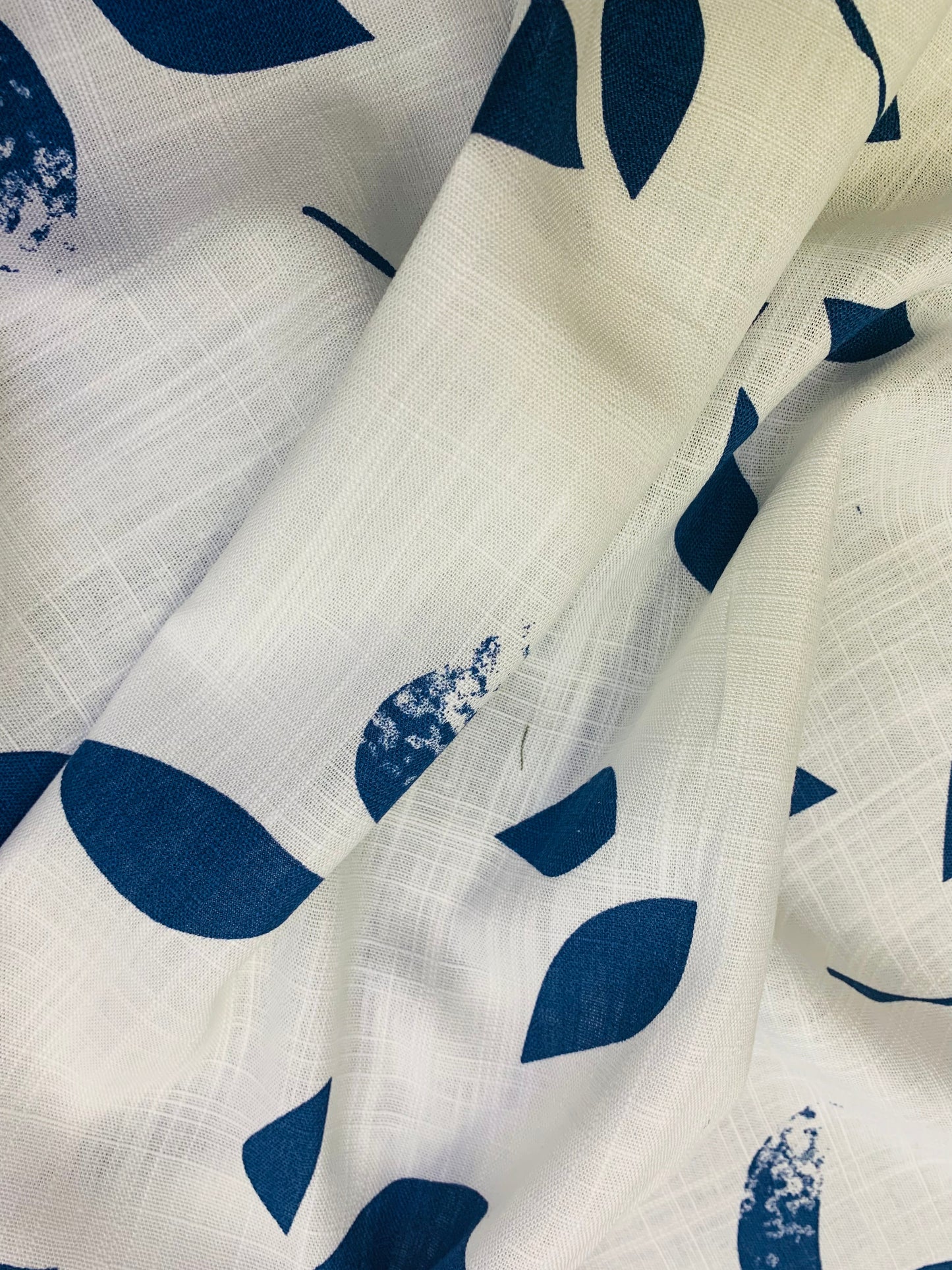 Pale fabric with dark blue leaves shows soft folds