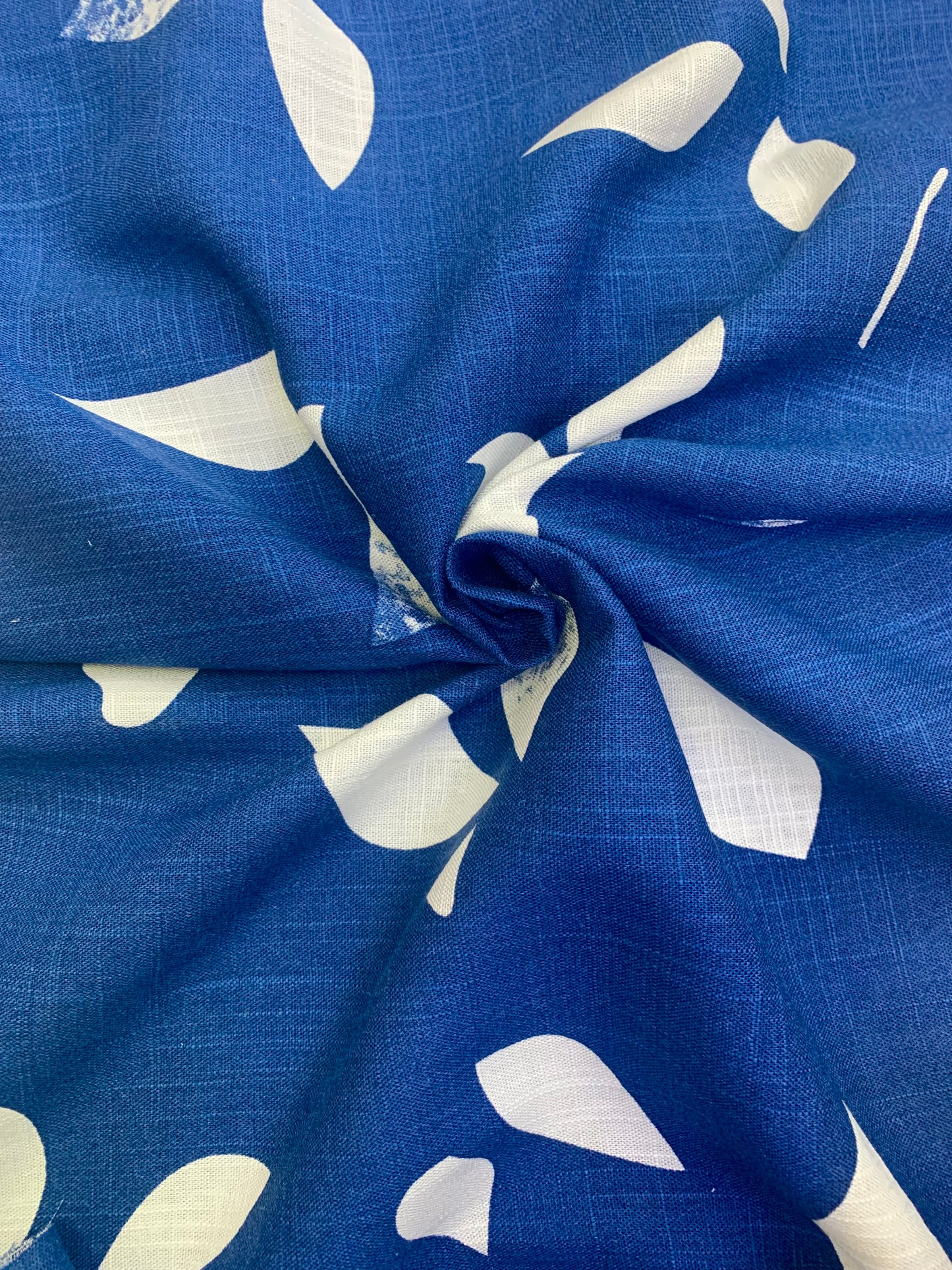 Blue fabric with white shapes is gathered into a central fold