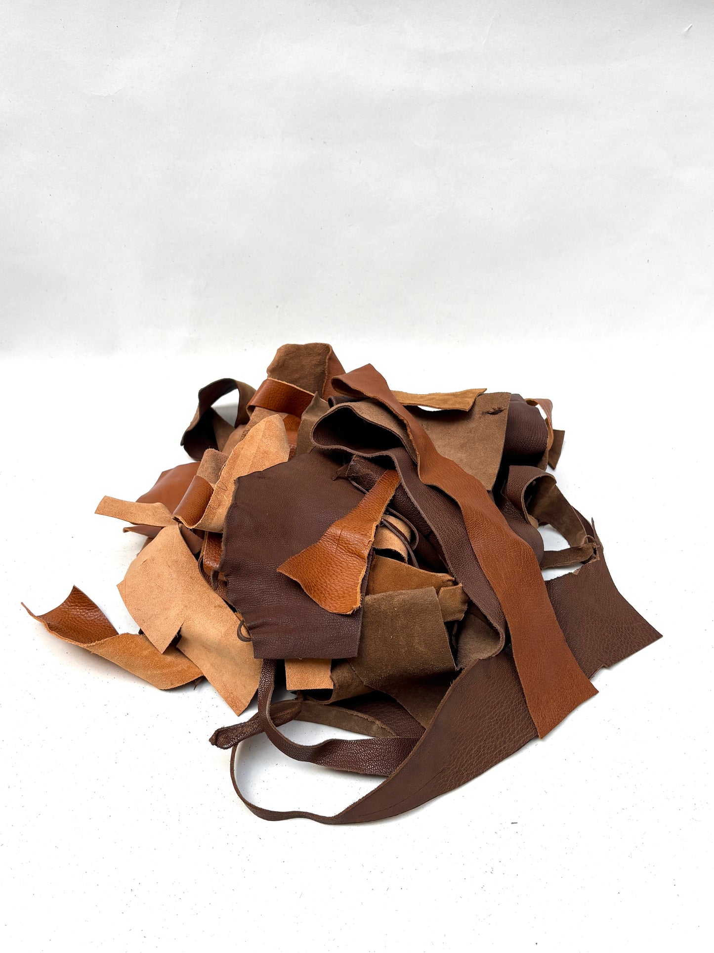 Mixed leather scraps in brown and tan tones are grouped together