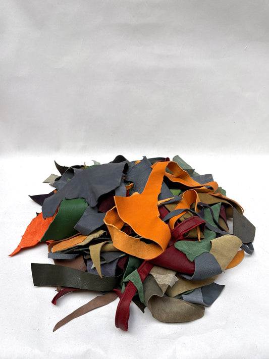 Mixed colourful material offcuts are piled on a white background