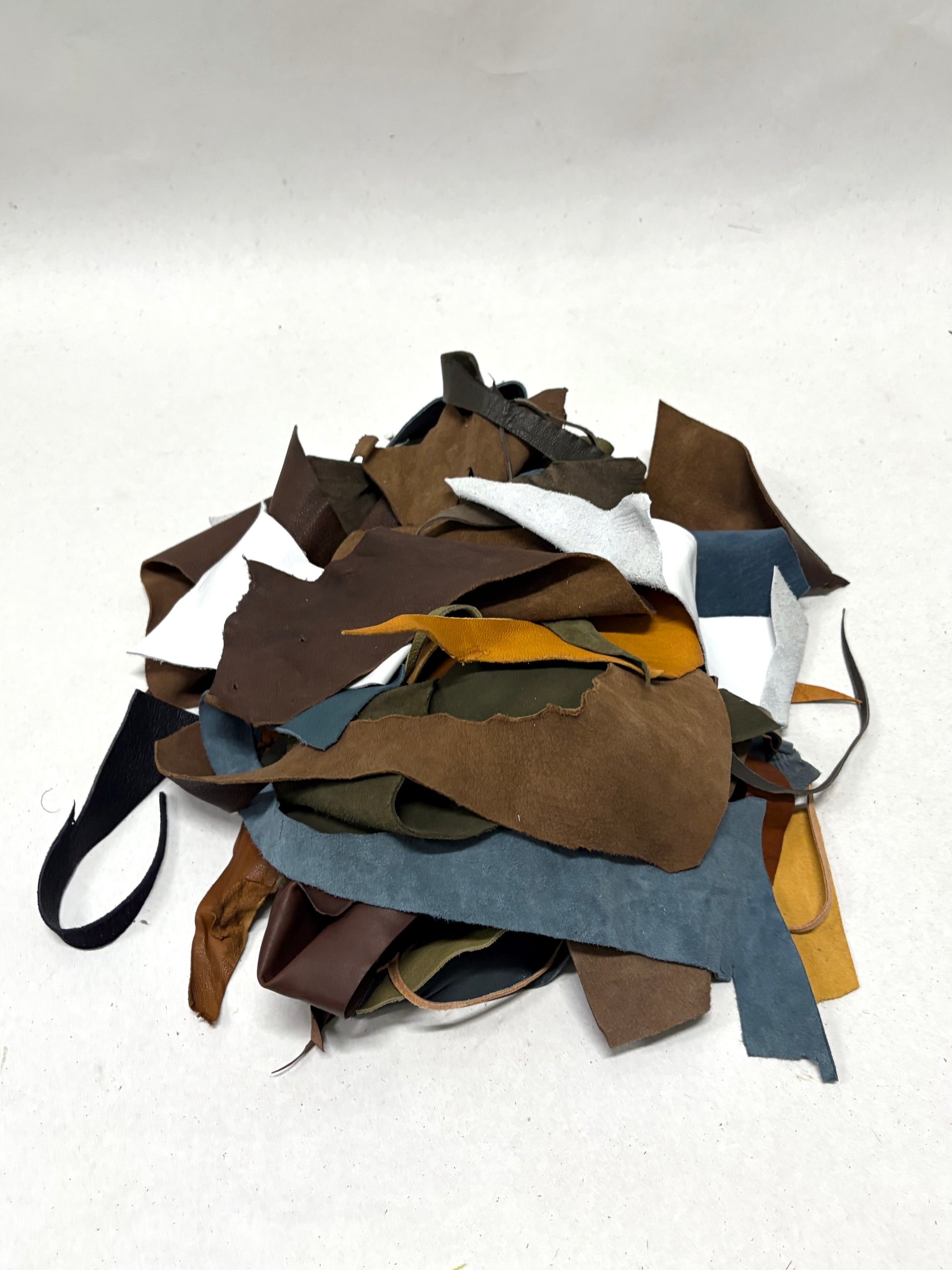 Pile of leather offcuts in various colors on a white background