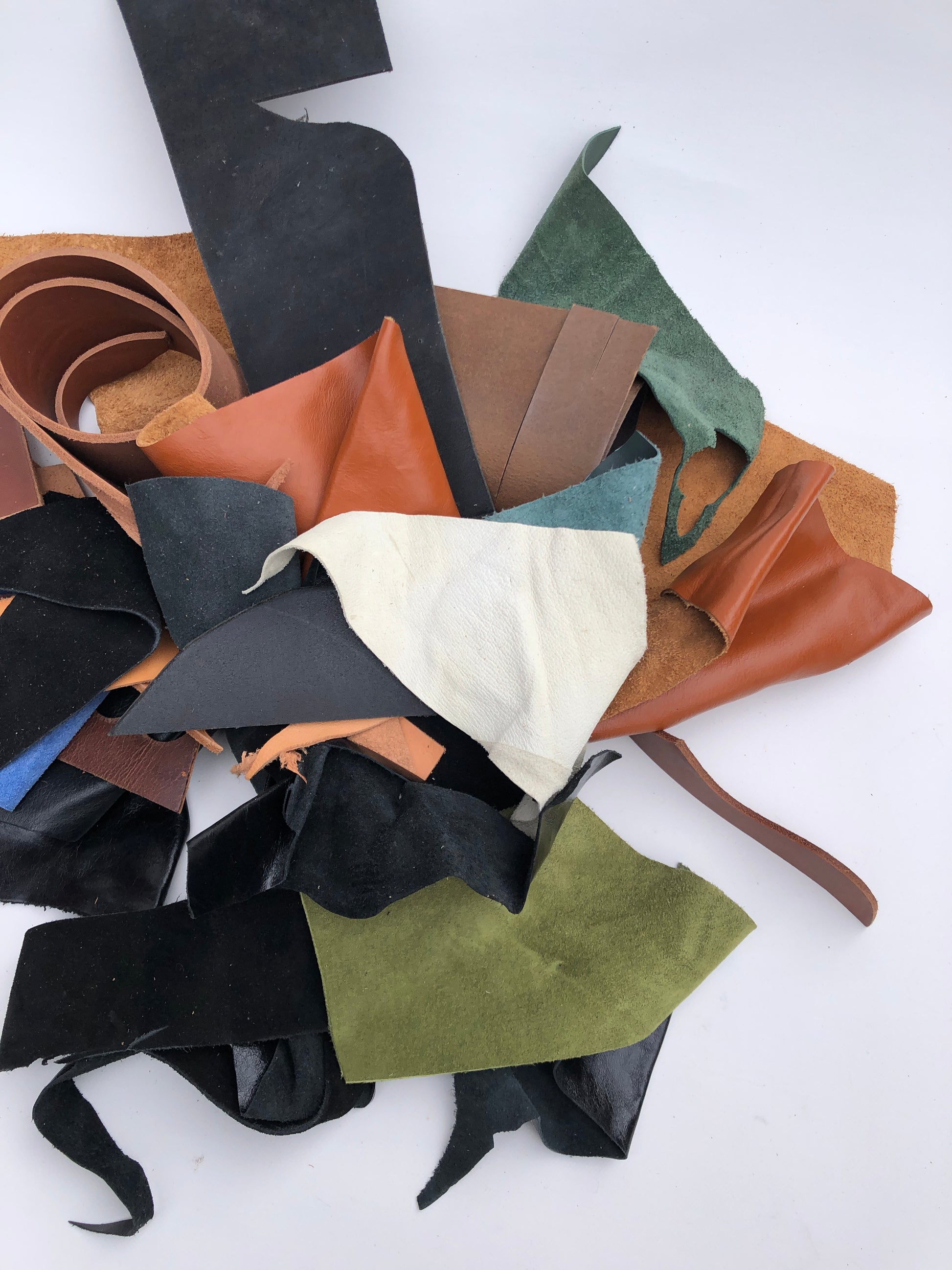 Collection of various leather offcuts in different colors on a white background