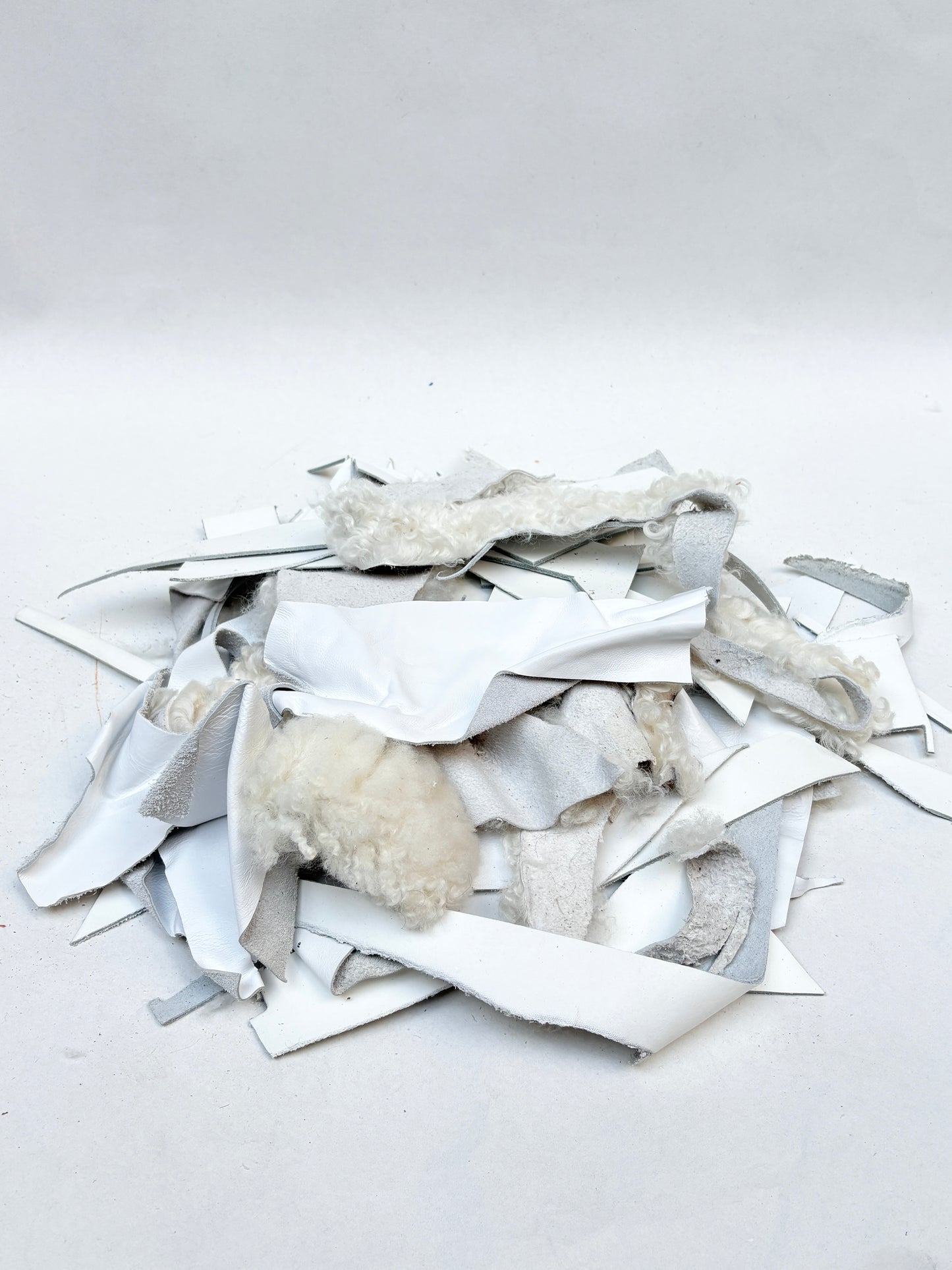 White material offcuts are piled on a white background