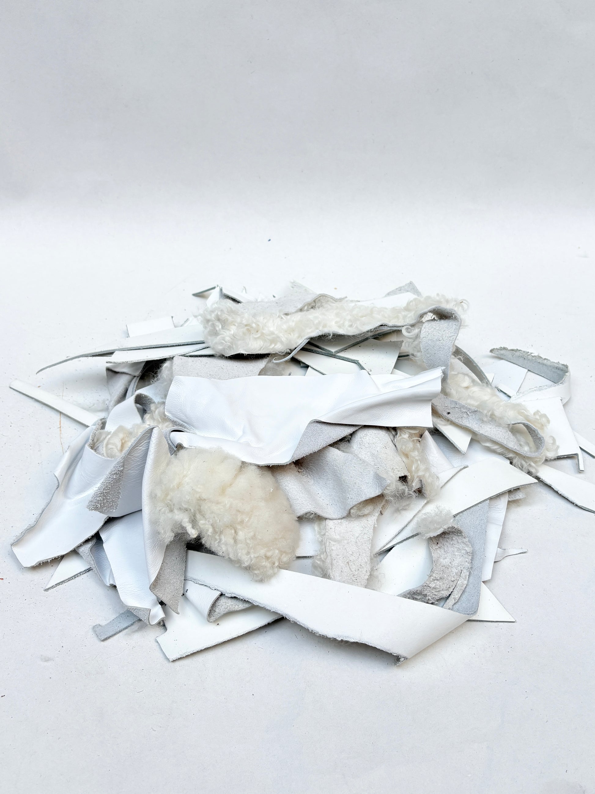 White material offcuts are piled on a white background
