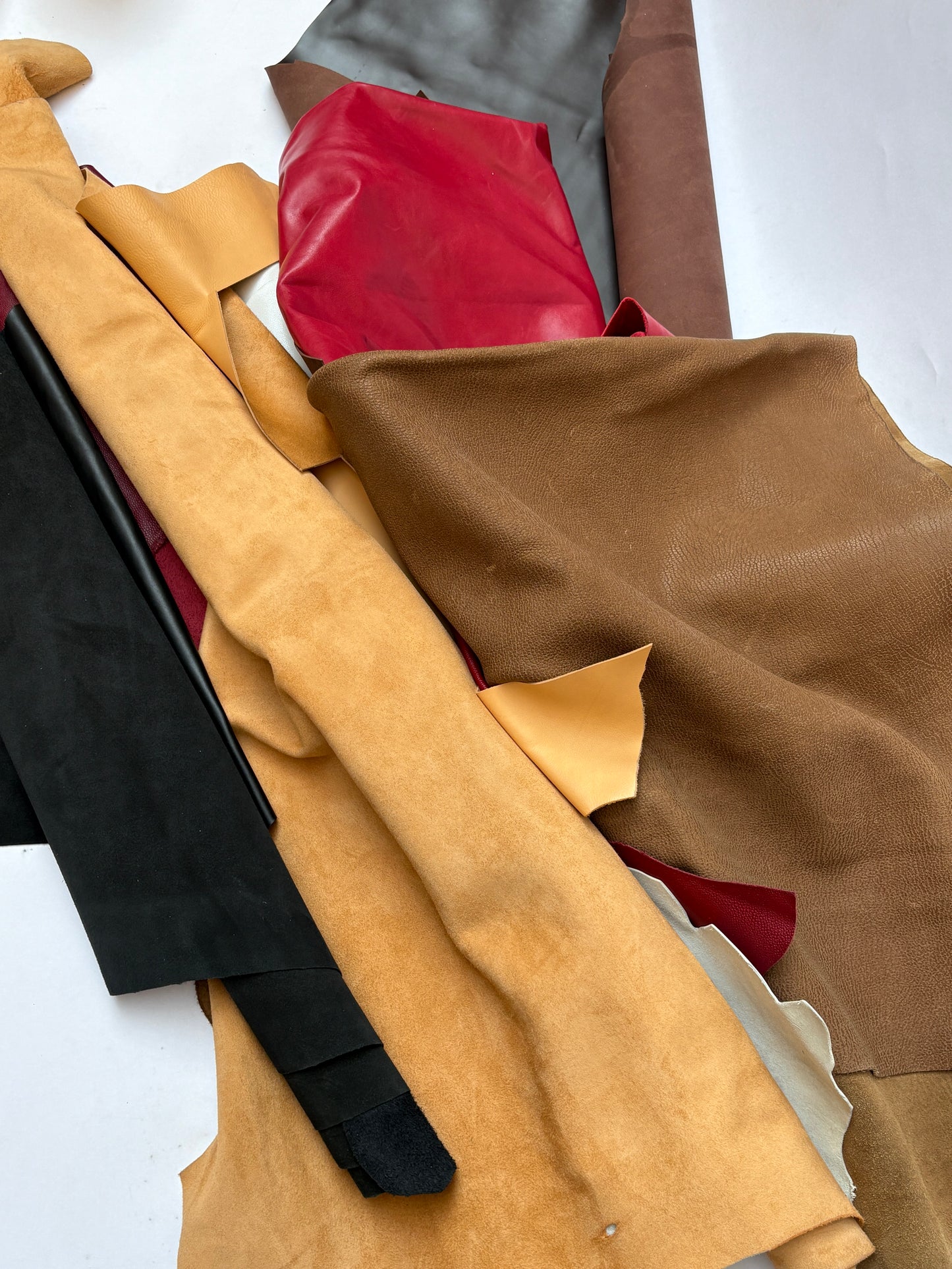 Close-up of various pieces of leather in different colors on a white background