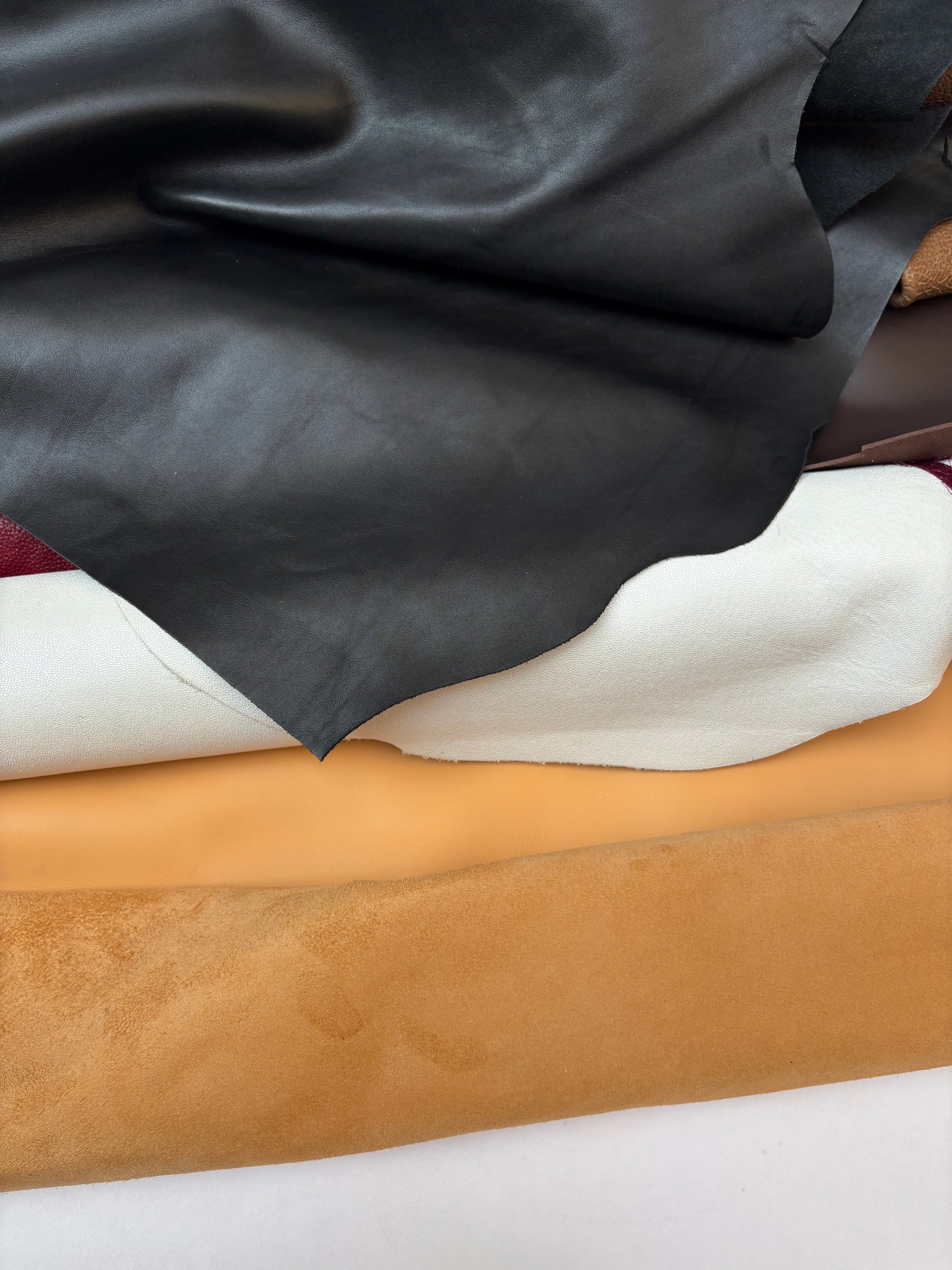 Close-up of black, white, and beige leathers on a white background