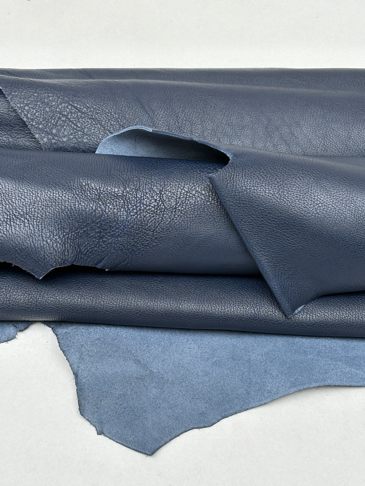 Blue leather material is draped with visible texture and creases