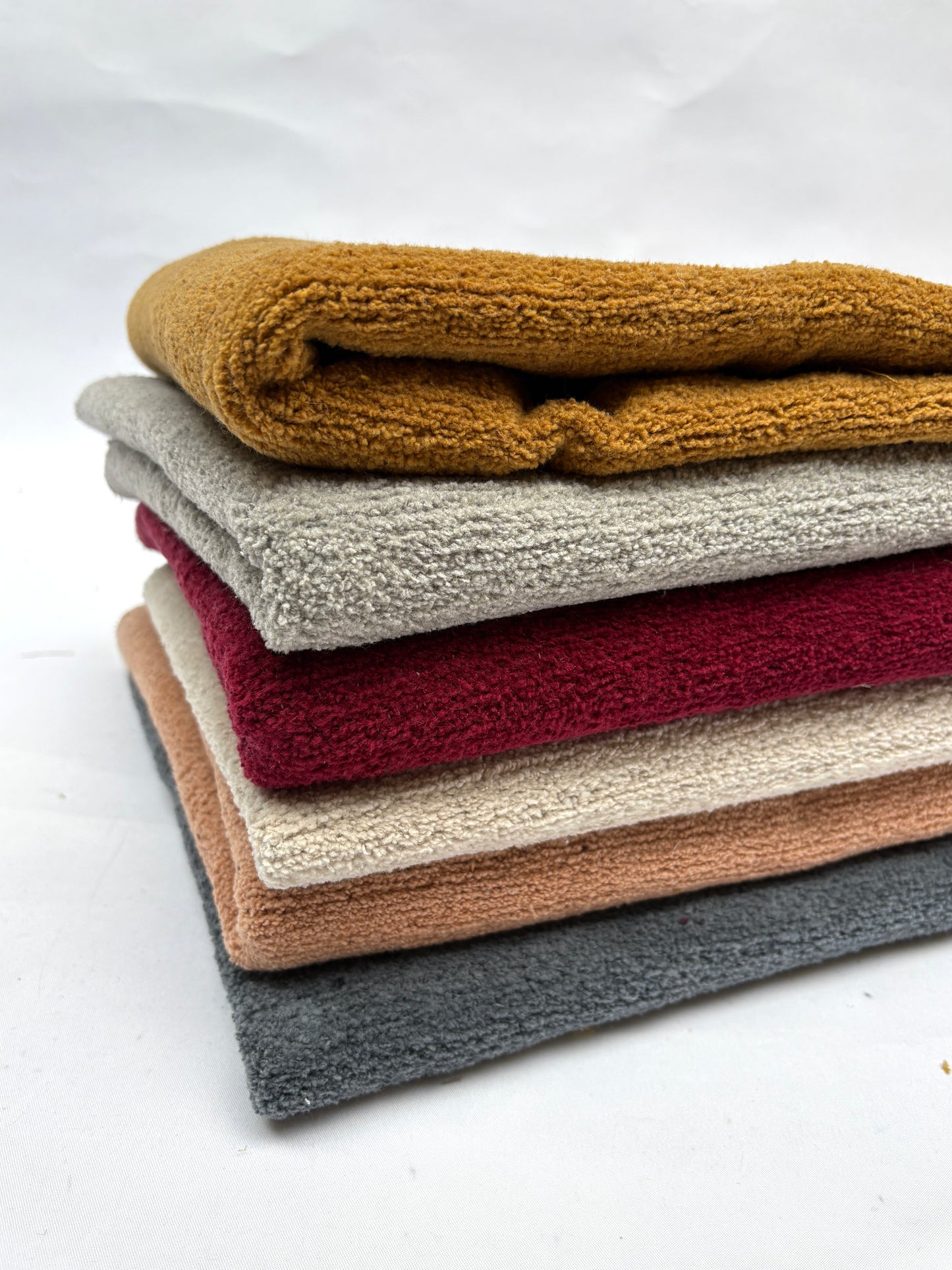 	Soft folded fabric pieces are shown in a stacked arrangement on white
